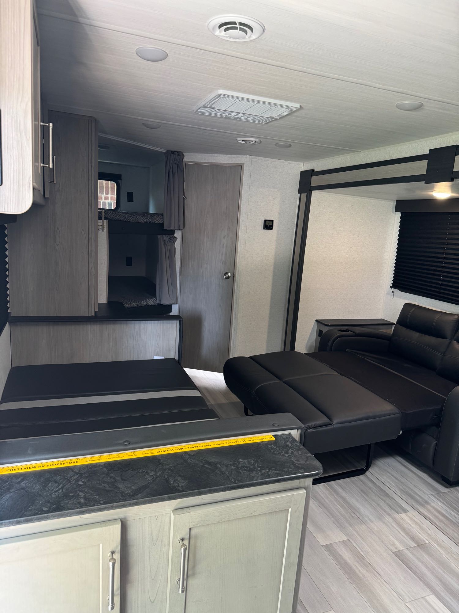 Spacious RV rental interior with bunk beds, reclining sofa, and convertible seating. Modern finish.. Keystone RV Springdale 25th Anniversary 2024