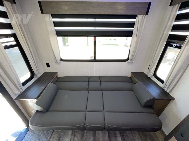 Spacious RV rental interior featuring a versatile gray sofa bed, large windows, and convenient side tables for comfortable travel.. Forest River 23MK 2024