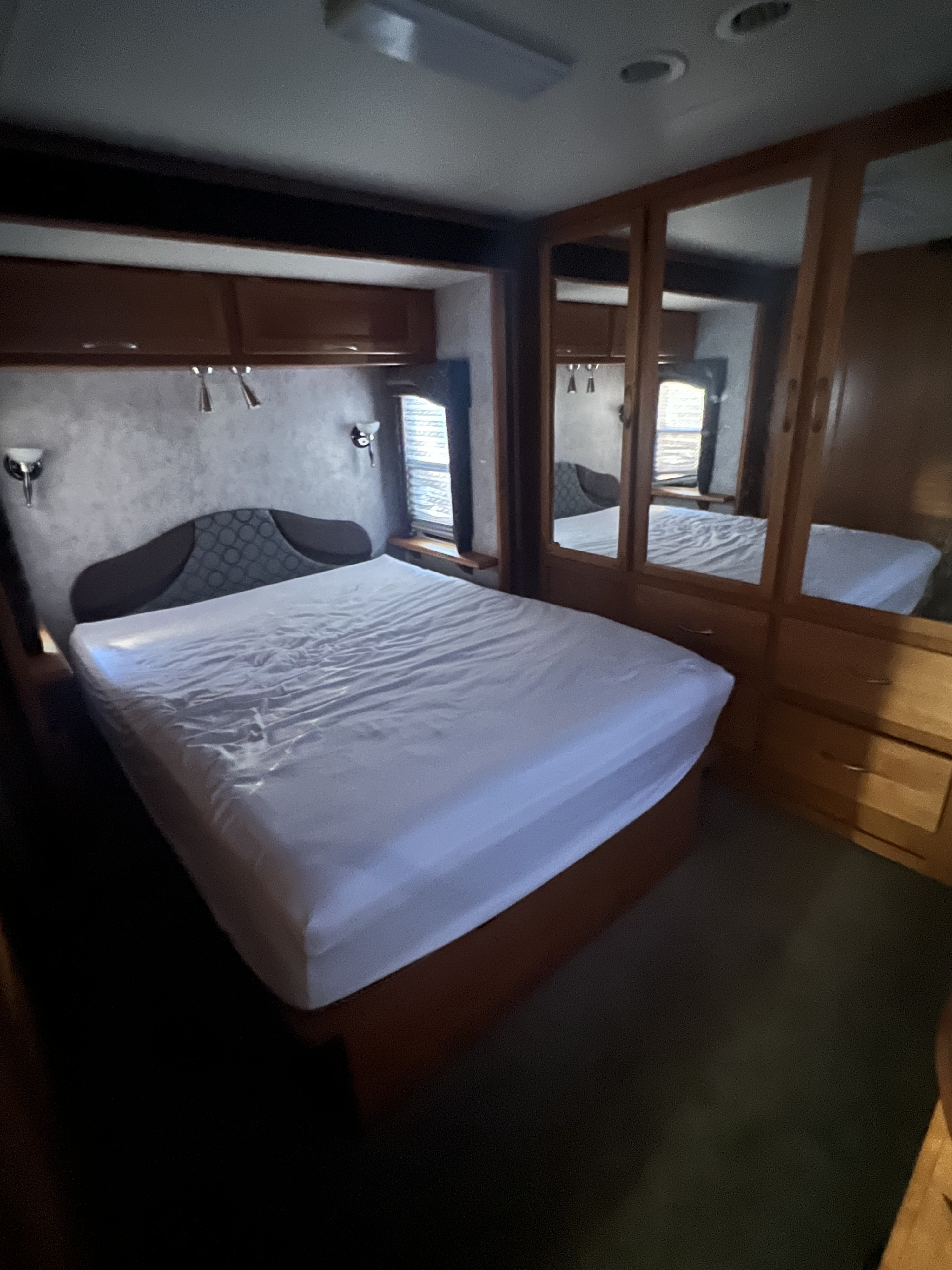 Inside an RV rental, this cozy bedroom features a pristine bed, headboard, and mirrored wardrobe.. Pace-Arrow Pace-Arrow Motorhome 2005