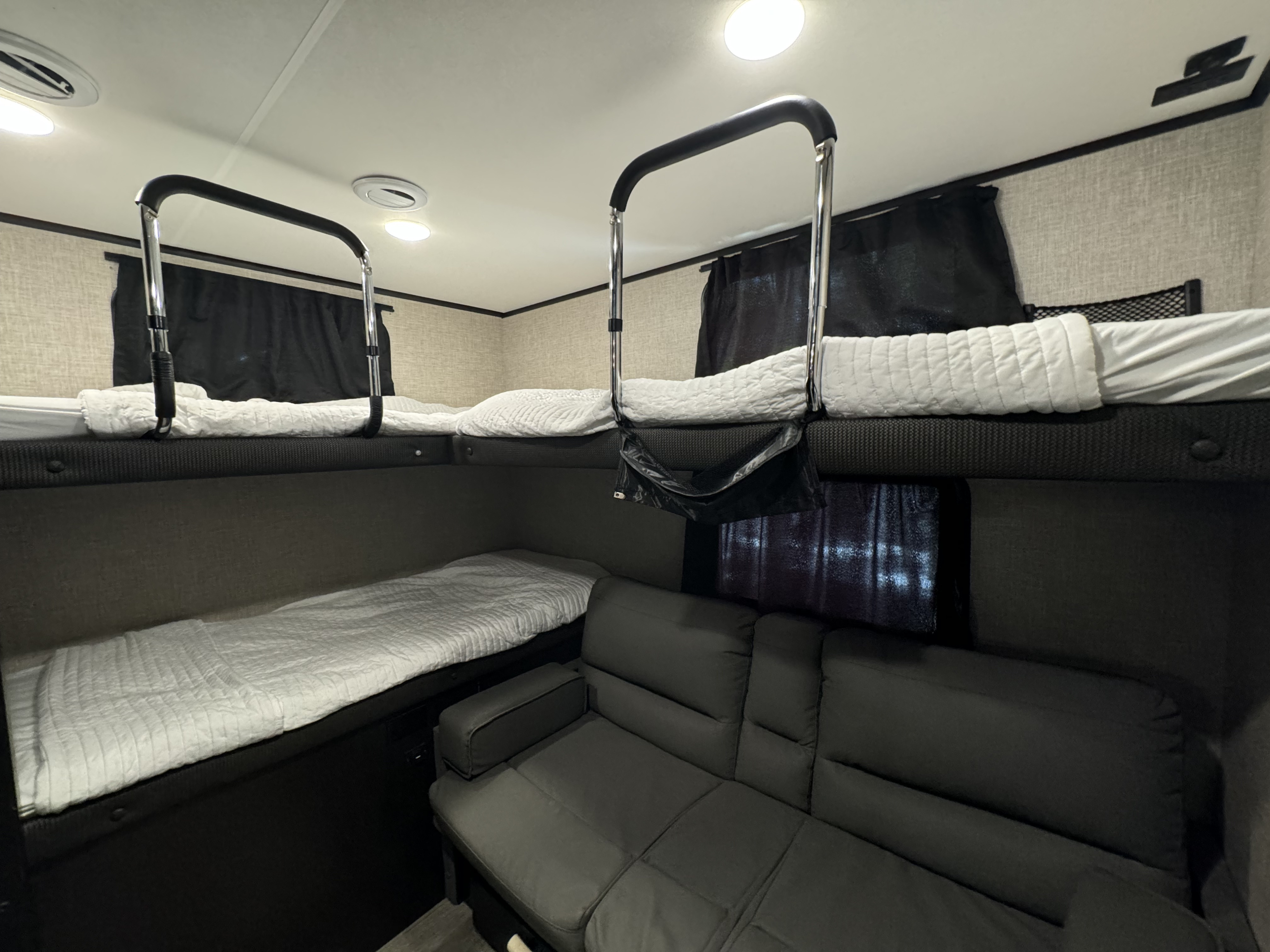 Cozy RV rental interior with bunk beds, safety rails, and a comfy sofa, perfect for families.. Jayco Jay Feather 2023
