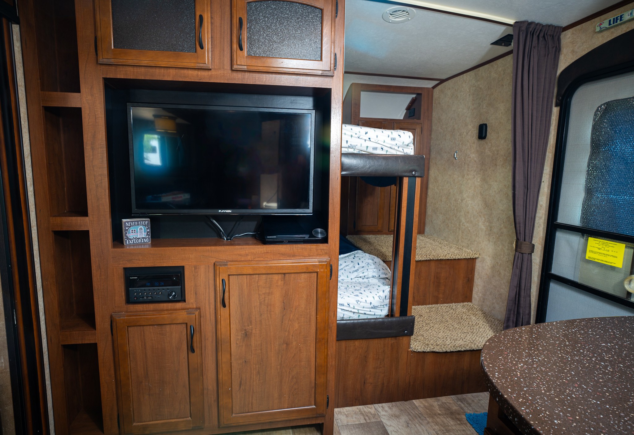 Compact rv rental interior with an entertainment center, bunk beds, and dining counter. Great for family adventures.. Jayco White Hawk 2016