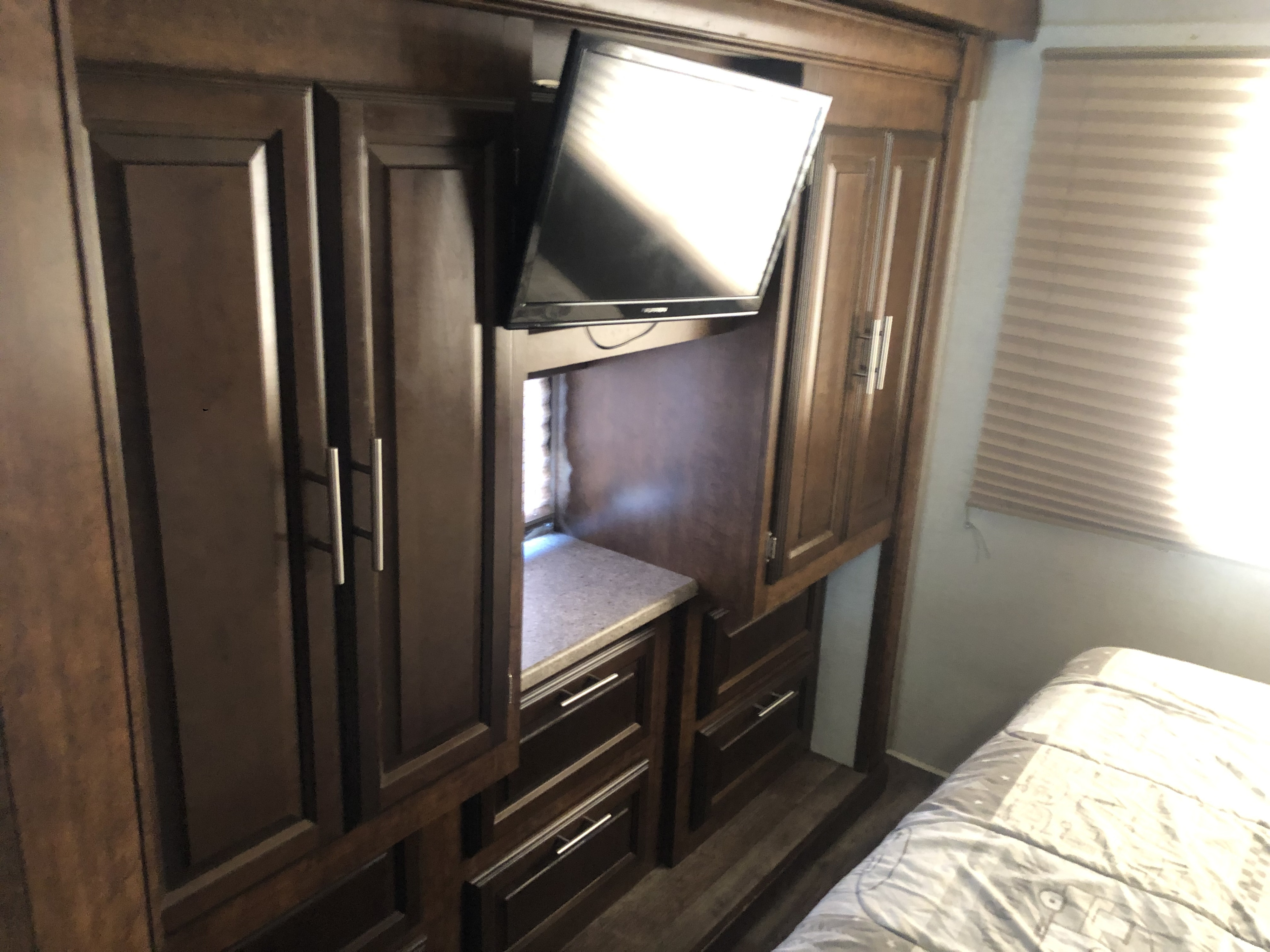 Explore this RV rental bedroom's dark wood cabinetry, mounted TV, and ample drawers for a comfortable stay.. FR3 FR3 Motorhome 2017