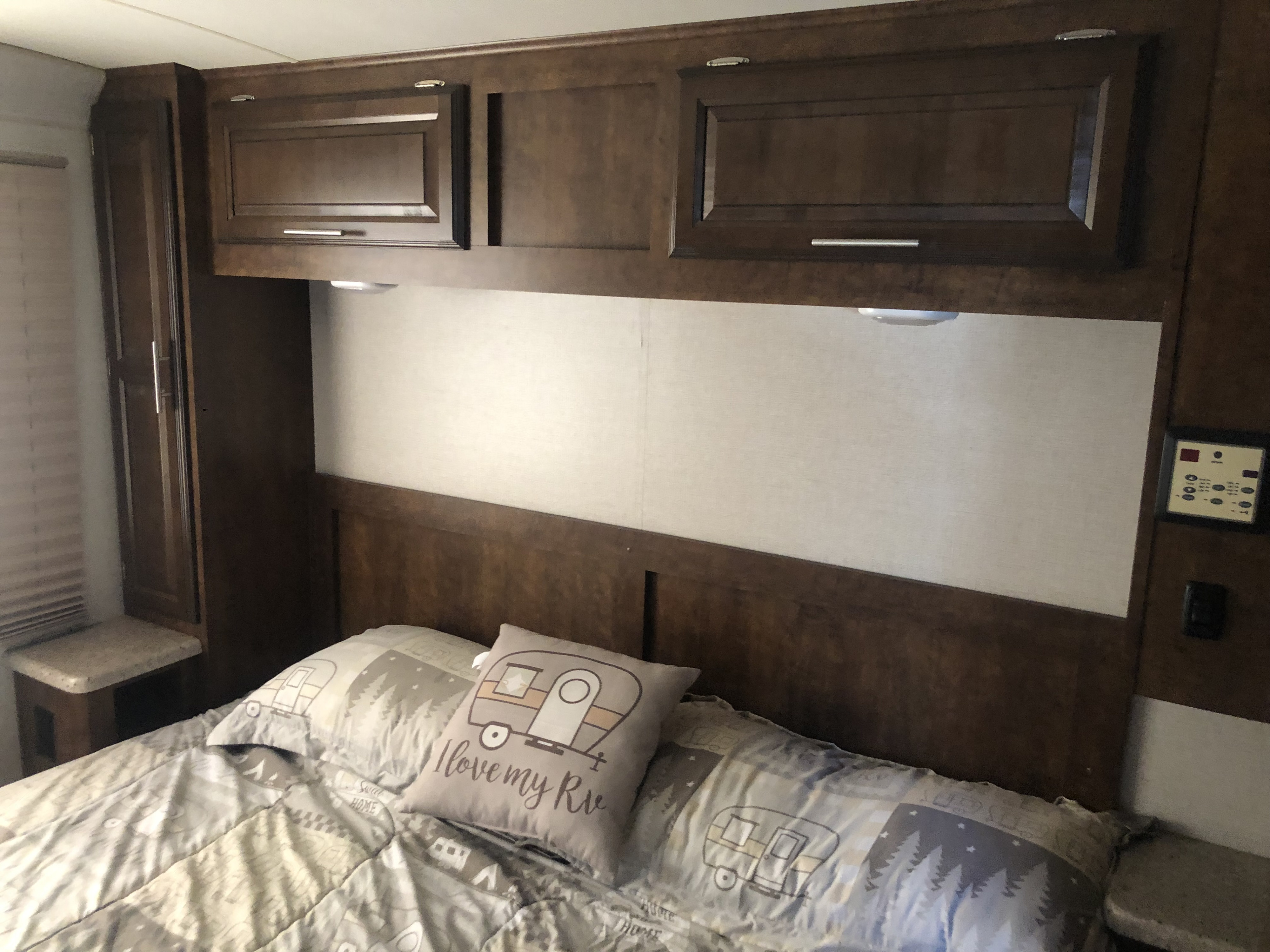 Cozy RV rental bedroom with patterned bedding, an "I love my RV" pillow, and dark wood overhead cabinets with reading lights.. FR3 FR3 Motorhome 2017