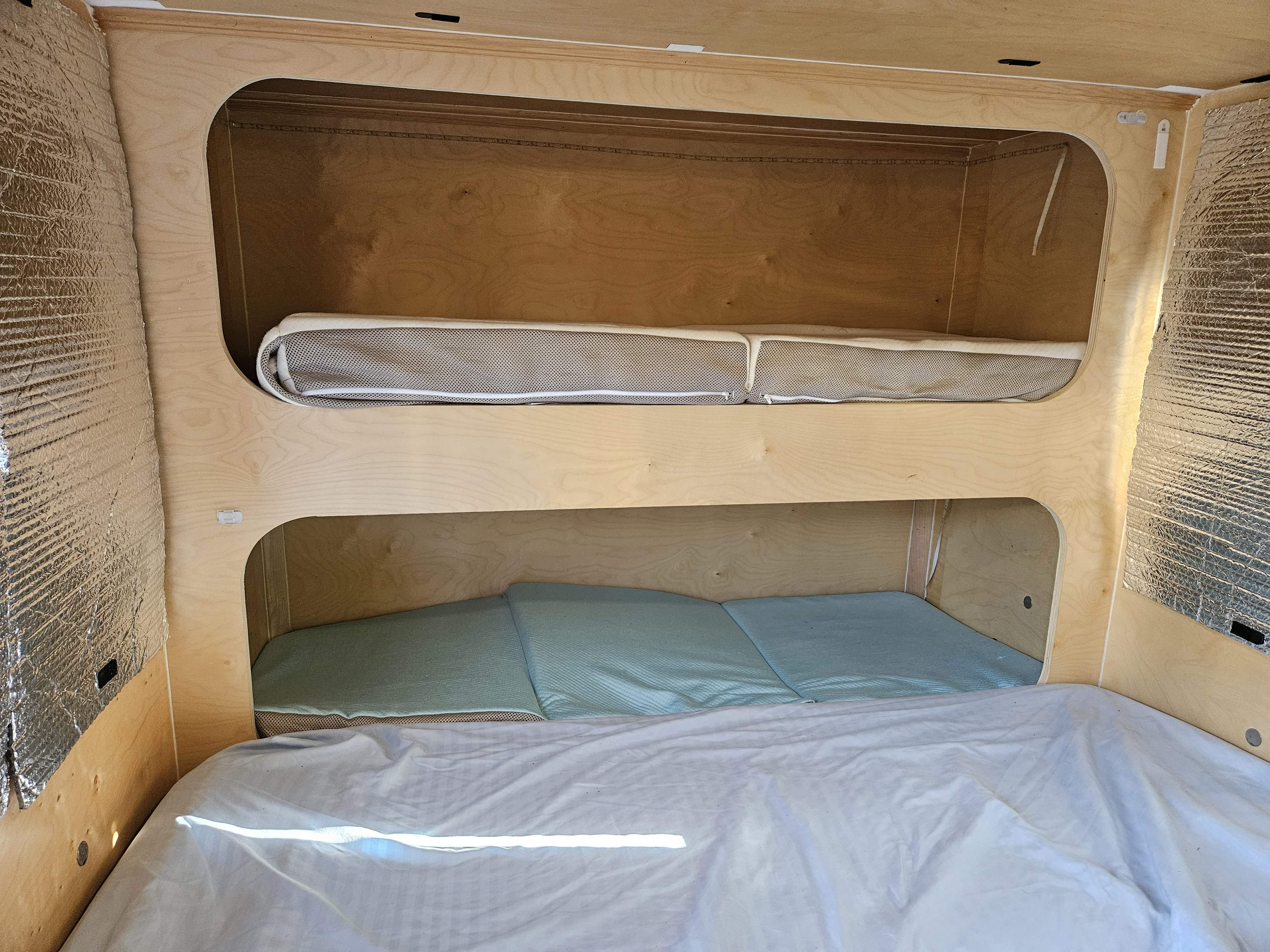Cozy rv rental interior with light wood bunk beds (top mesh, bottom blue mattress) & insulated walls.. Other Other 2021