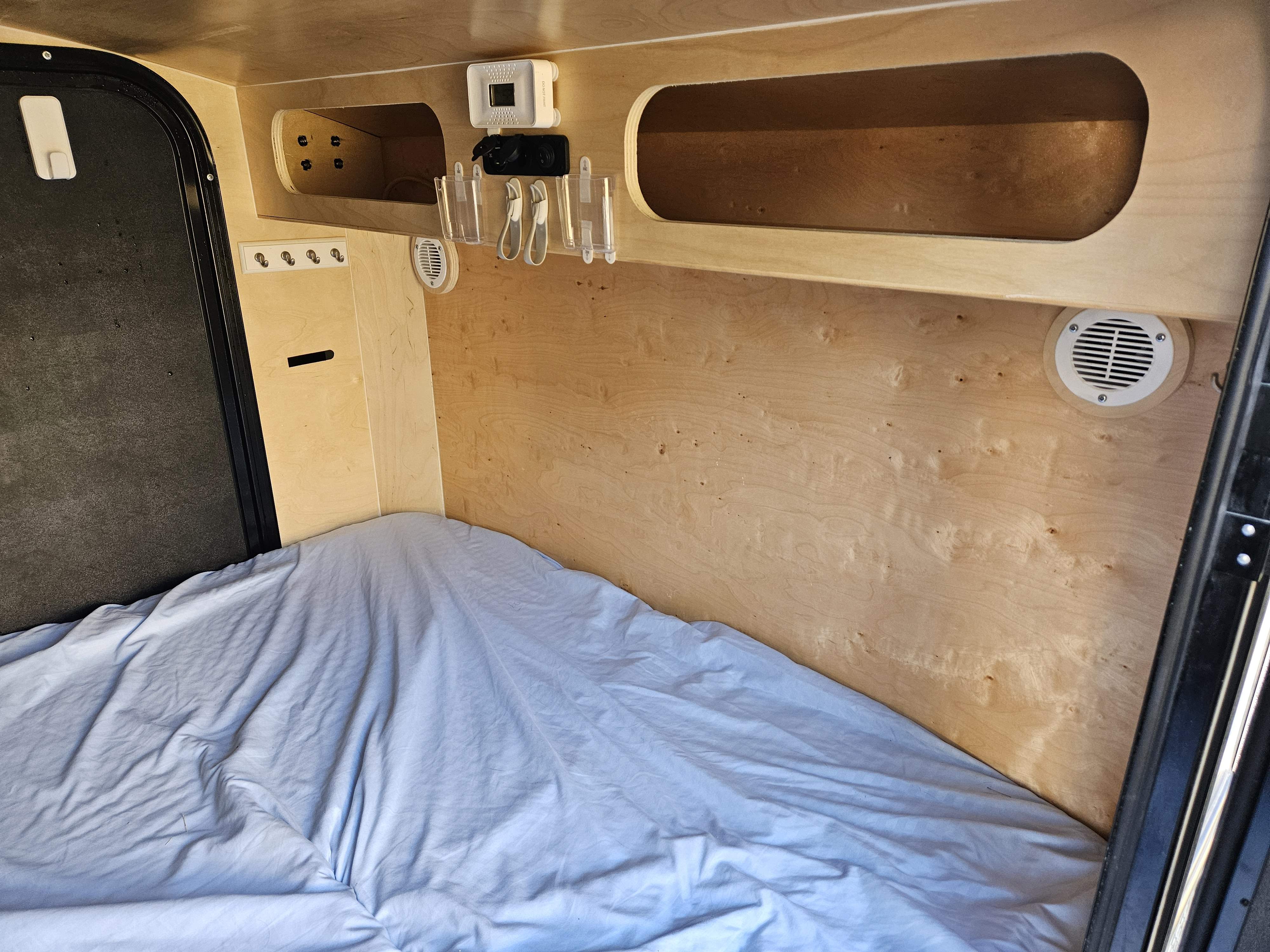 Inside a cozy RV rental: bed, wood walls, CO detector, charging port, and storage. Ideal for adventurers.. Other Other 2021