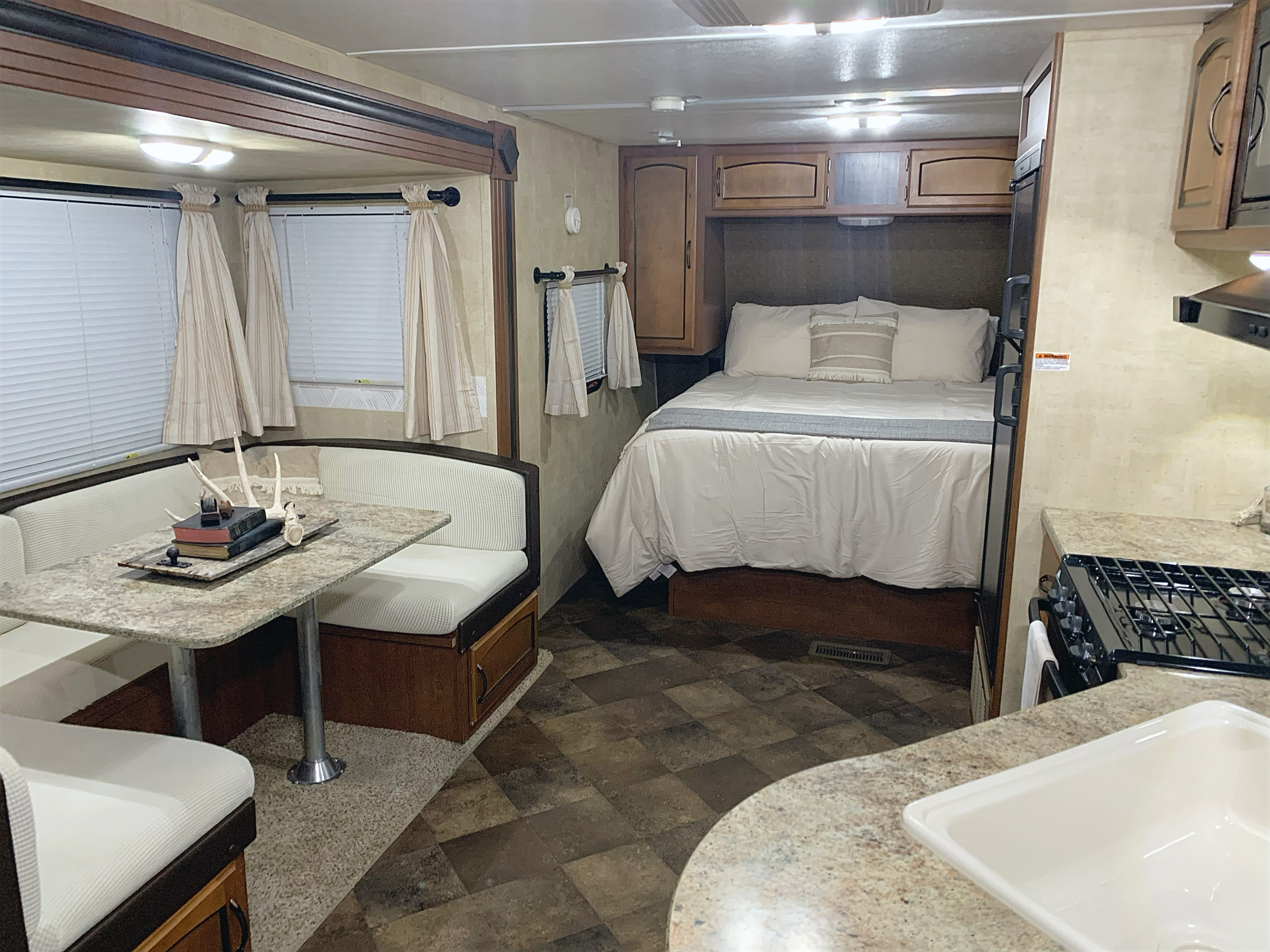 Experience comfort in this RV rental: interior shows a bright bedroom, cozy dining booth, and compact kitchen.. Keystone RV Summerland 2013