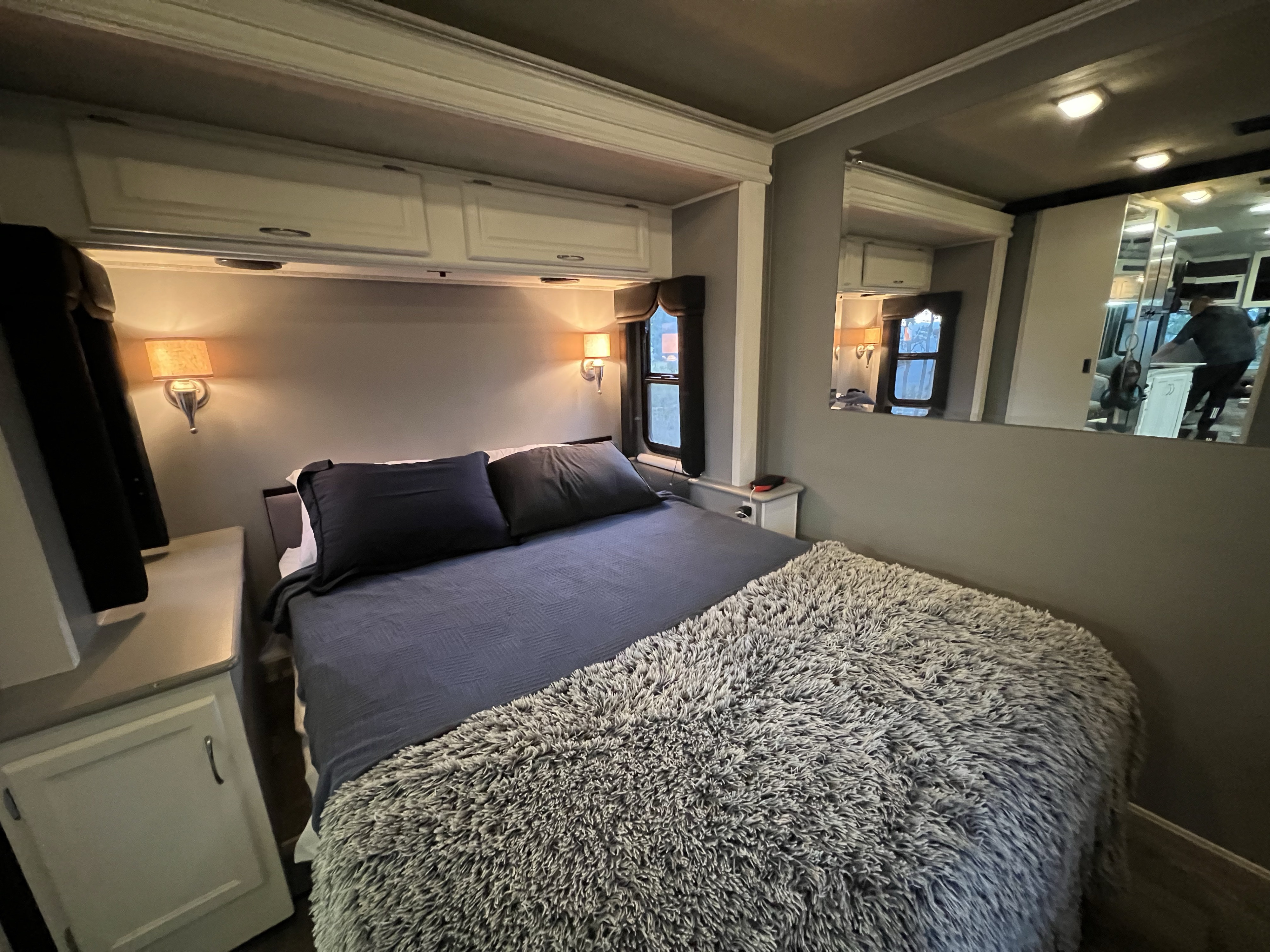 Spacious RV rental bedroom featuring a comfy bed, wall lamps, and ample storage cabinetry.. Fleetwood Southwind 32VS 2006