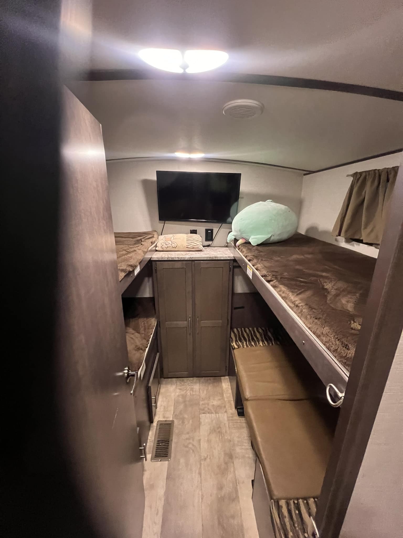 RV rental interior features bunk beds with brown blankets, a central TV, and a bench, ideal for family travel.. Crossroads RV Sunset Trail Super Lite 2018