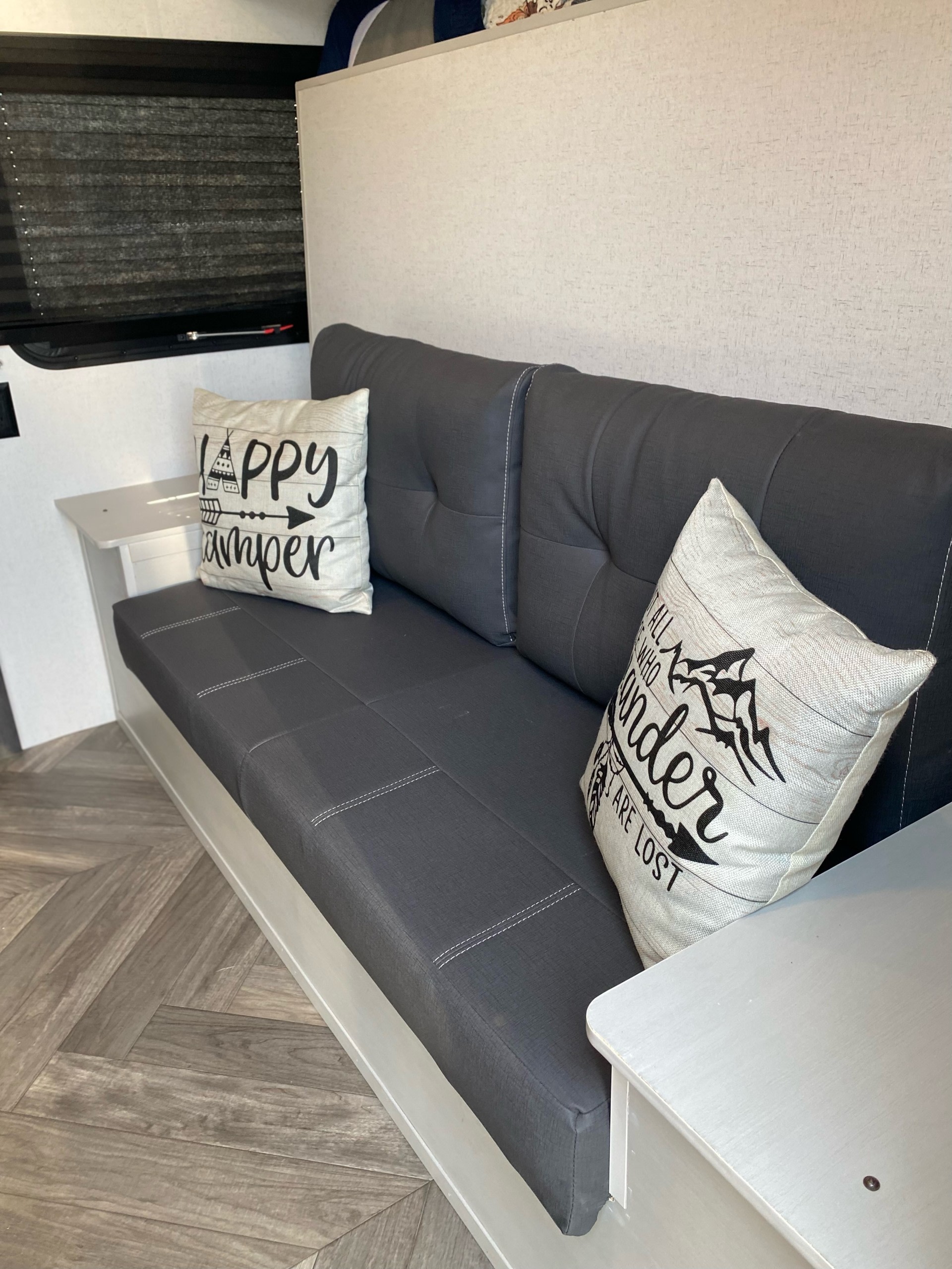 RV rental's inviting interior: gray sofa with accent pillows, built-in side tables, and chic wood-style floor.. Forest River Salem FSX 2022