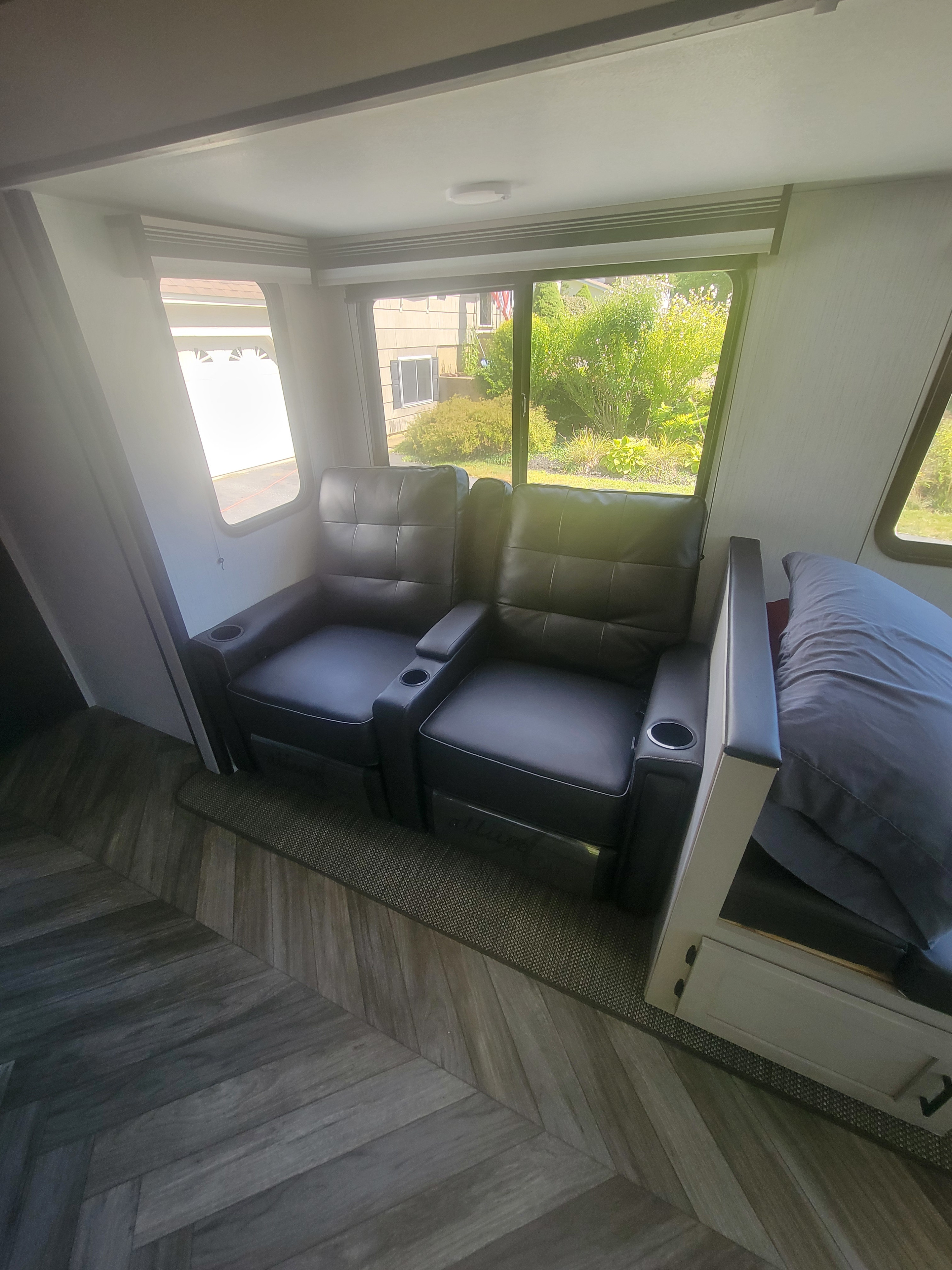 Comfortable RV rental interior with dual recliners, large windows offering scenic views, and modern wood-look flooring.. Heartland RVs Mallard 2023