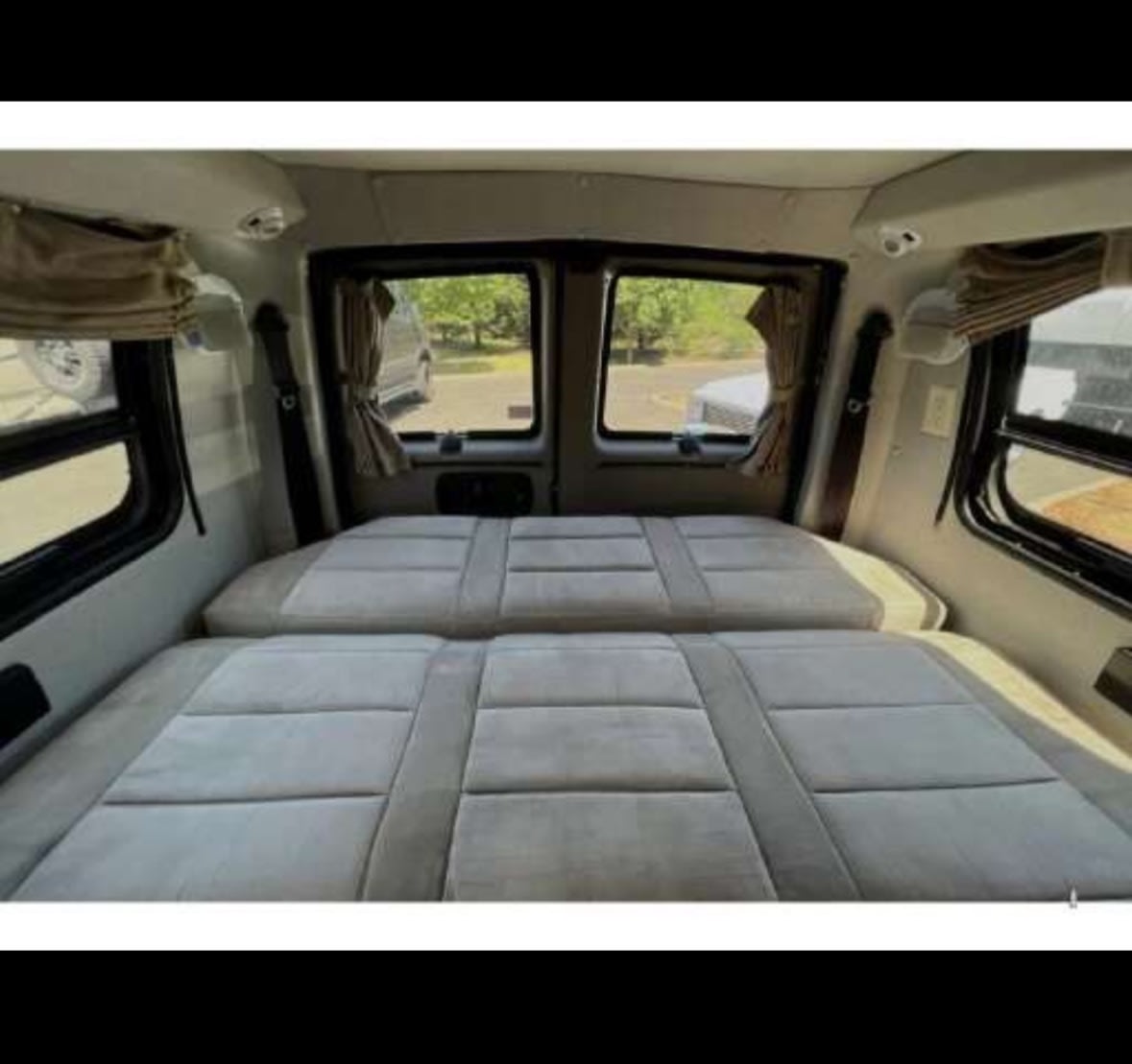 Interior of an RV rental: two comfy beds side-by-side, with windows and curtains. Perfect camper van for travel.. Roadtrek Roadtrek Class B 2010