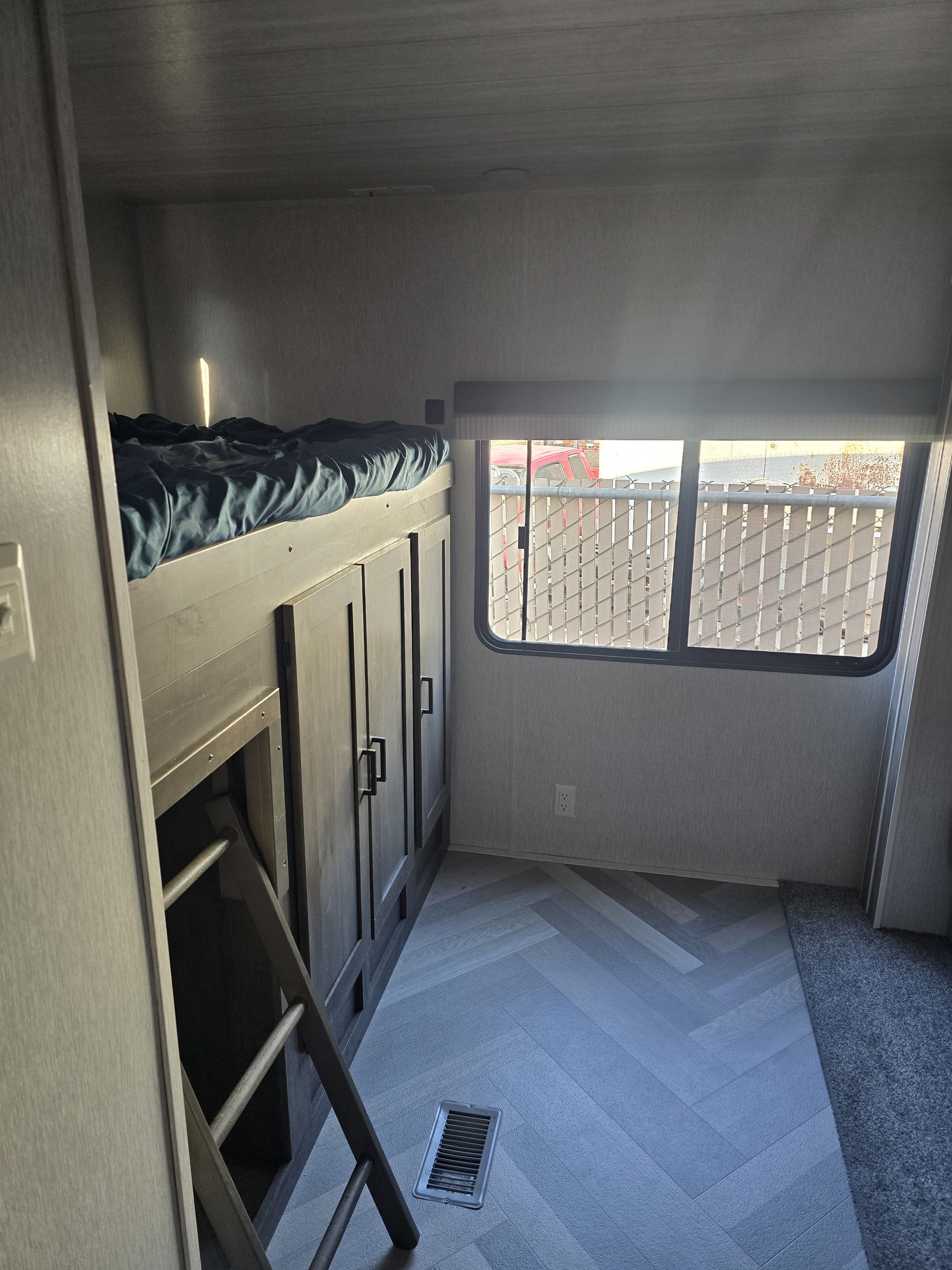 This RV rental features a cozy bunk bed setup with integrated storage, a window view, and stylish herringbone flooring.. Forest River Wildwood 2022