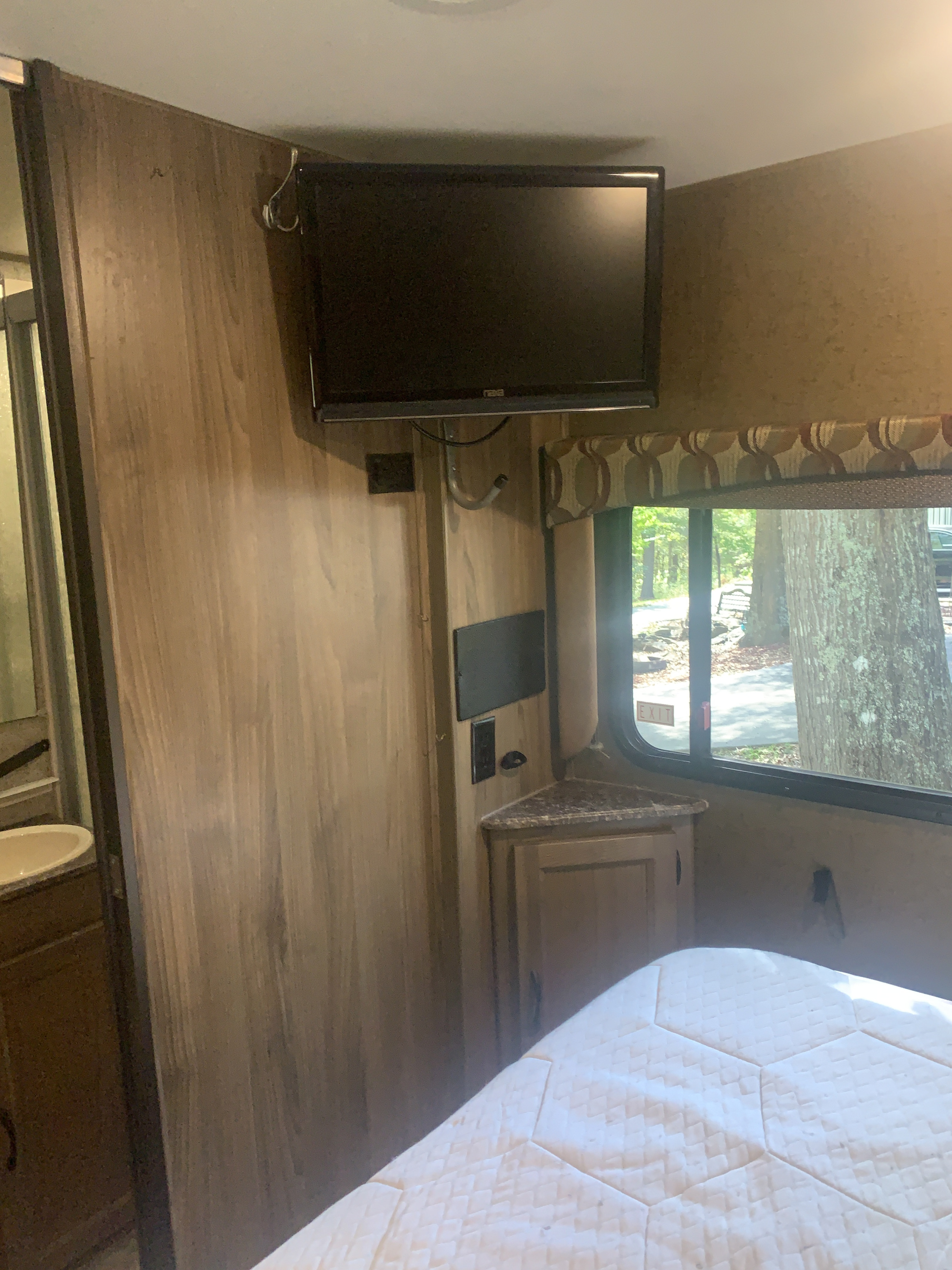 RV rental bedroom: interior with bed, wall-mounted TV, window view, and partial bathroom on left.. Forest River Coachmen Freelander 2017