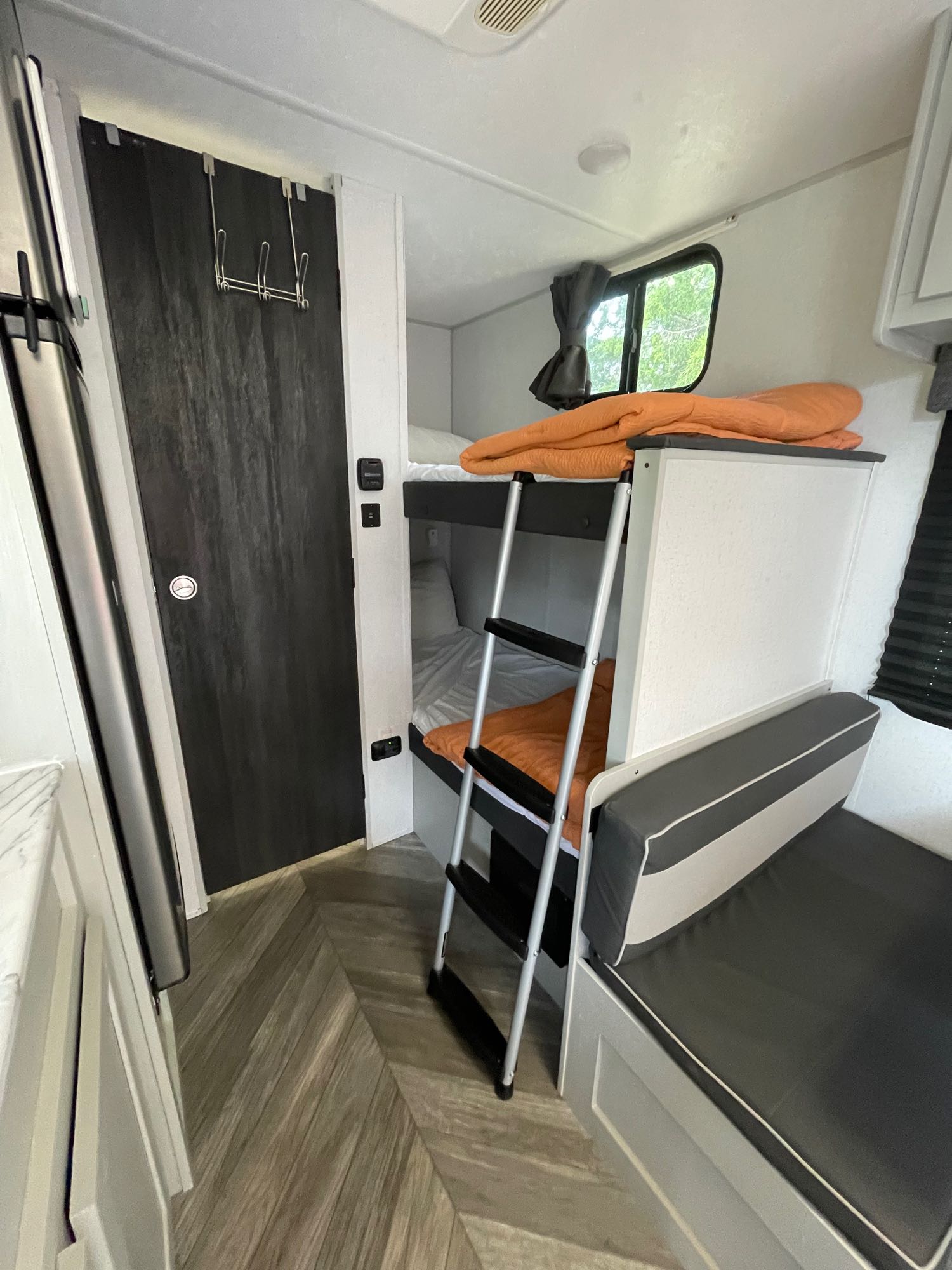 RV rental interior: Bunk beds with ladder, dinette, and sleek dark door, offering compact comfort for trips.. Forest River Salem FSX Plantium 2022