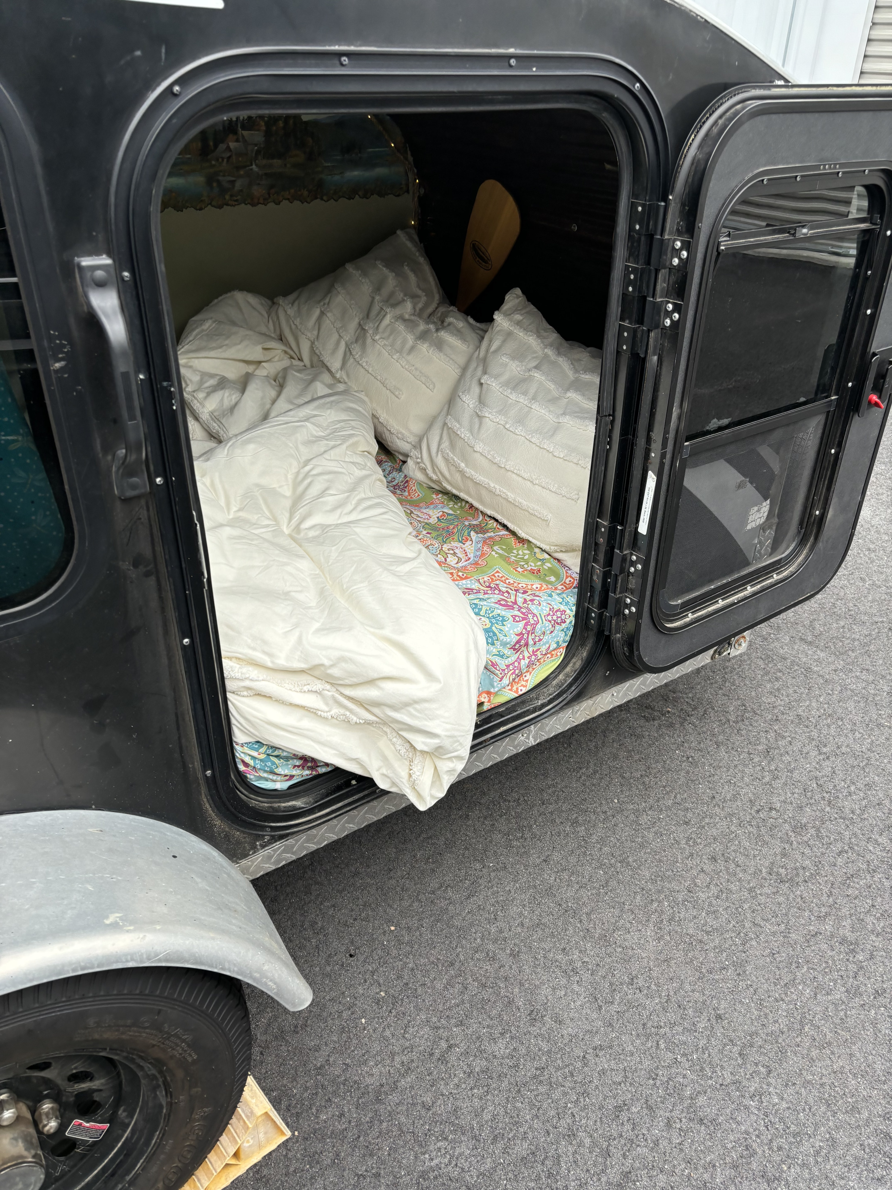 Cozy teardrop camper interior. This RV rental features a comfortable bed, paddle, & scenic mural, ready for adventure.. Signatory Tote+4 2014