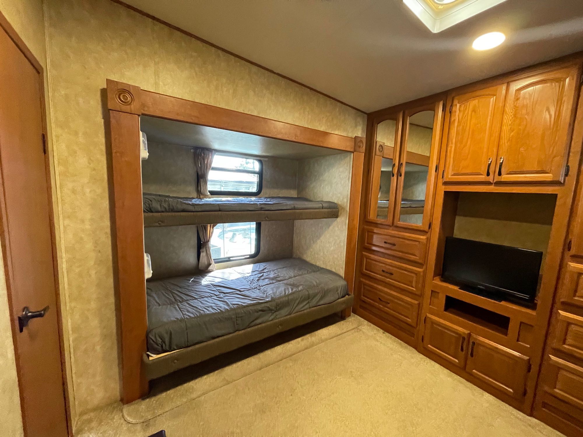 RV rental: well-equipped sleeping area with sturdy bunk beds, built-in TV, and ample wood cabinetry.. Forest River Sandpiper 2011