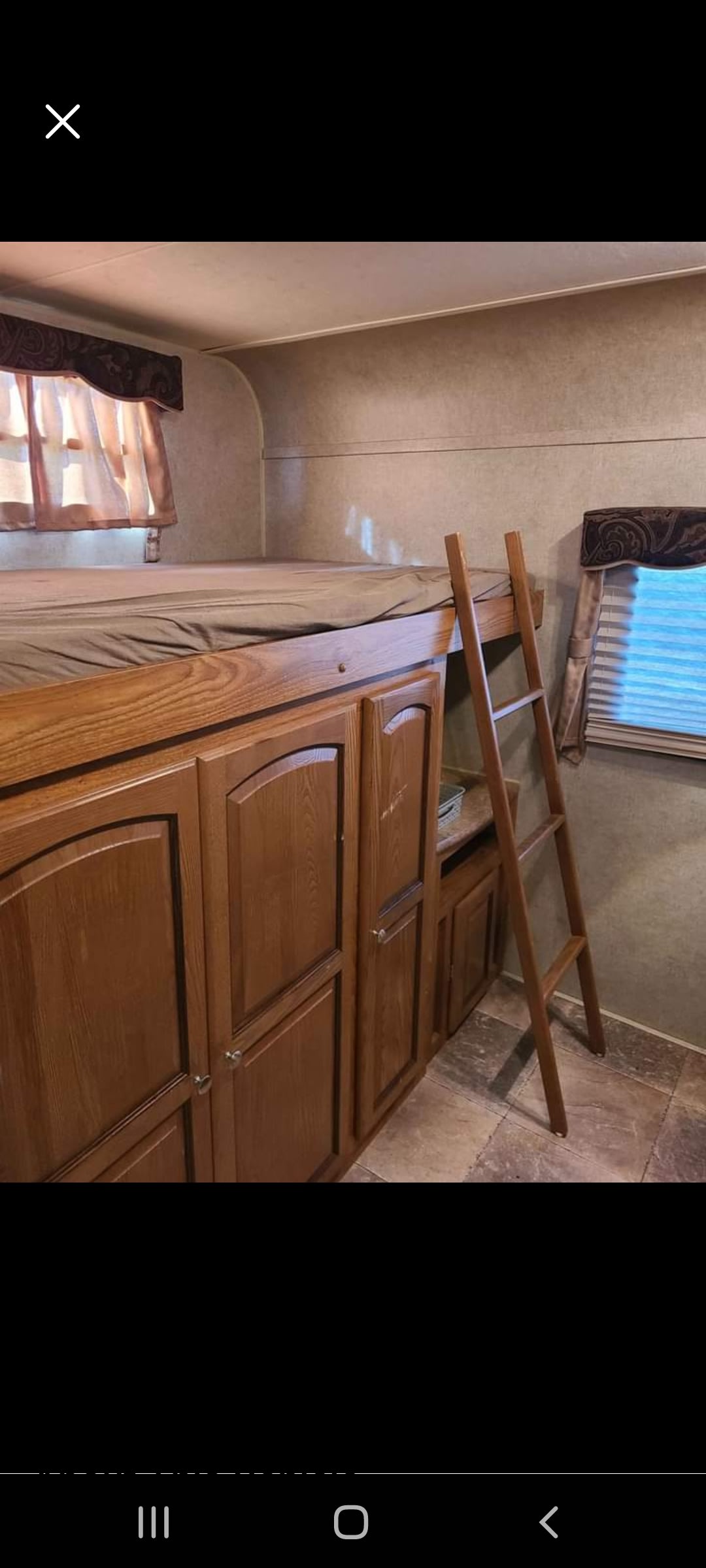 View of an RV rental interior: bunk bed over wood cabinets, with ladder, window, and tiled floor.. Forest River Rockwood Signature Ultra Lite 2012