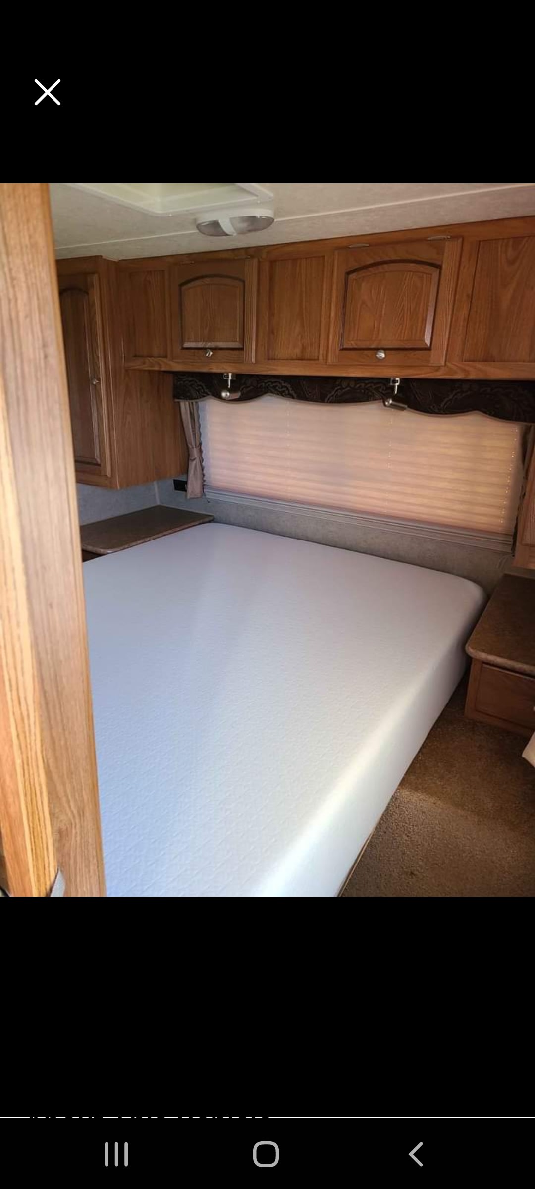 Comfortable RV rental bedroom with a white bed, wooden cabinets, and window blinds. Perfect for travel.. Forest River Rockwood Signature Ultra Lite 2012