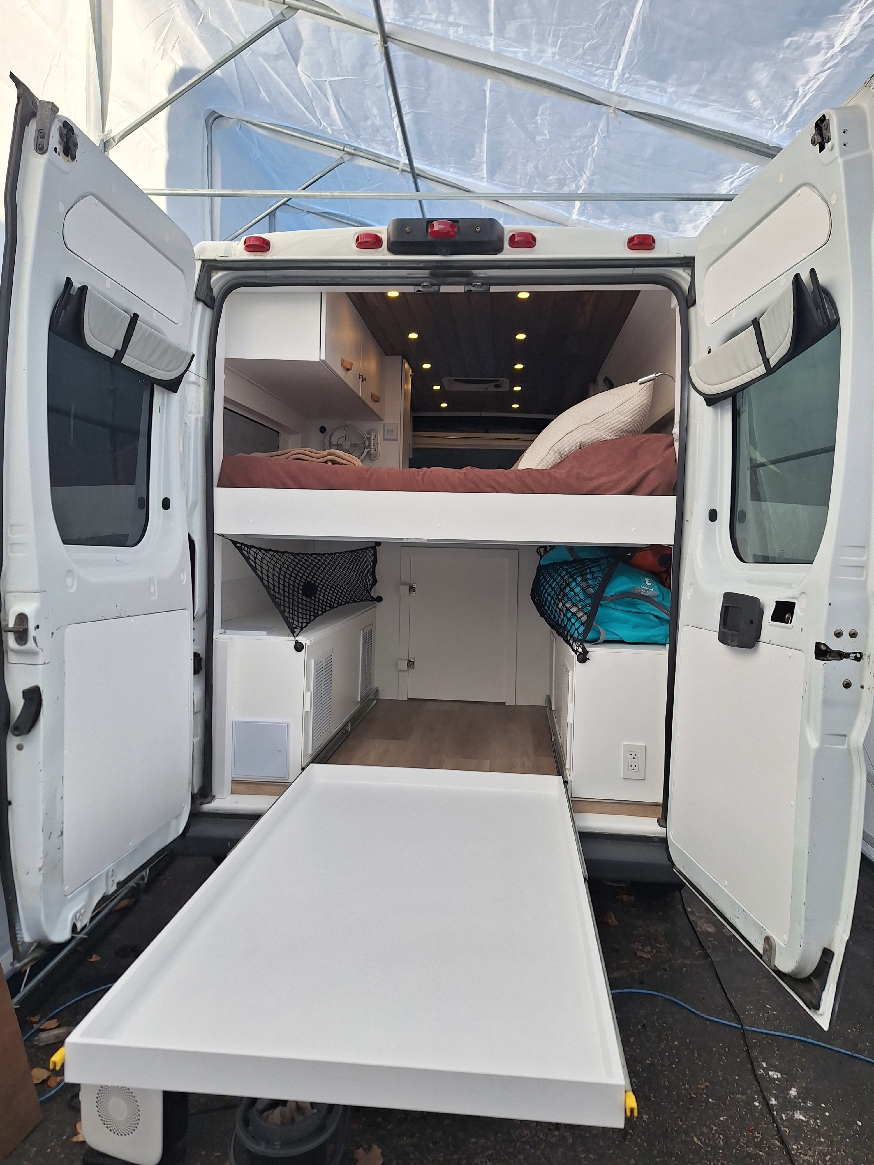 Spacious RV rental interior showcasing a comfortable bed, smart storage, and a pull-out platform for mobile adventures.. Ram Promaster Other 2014