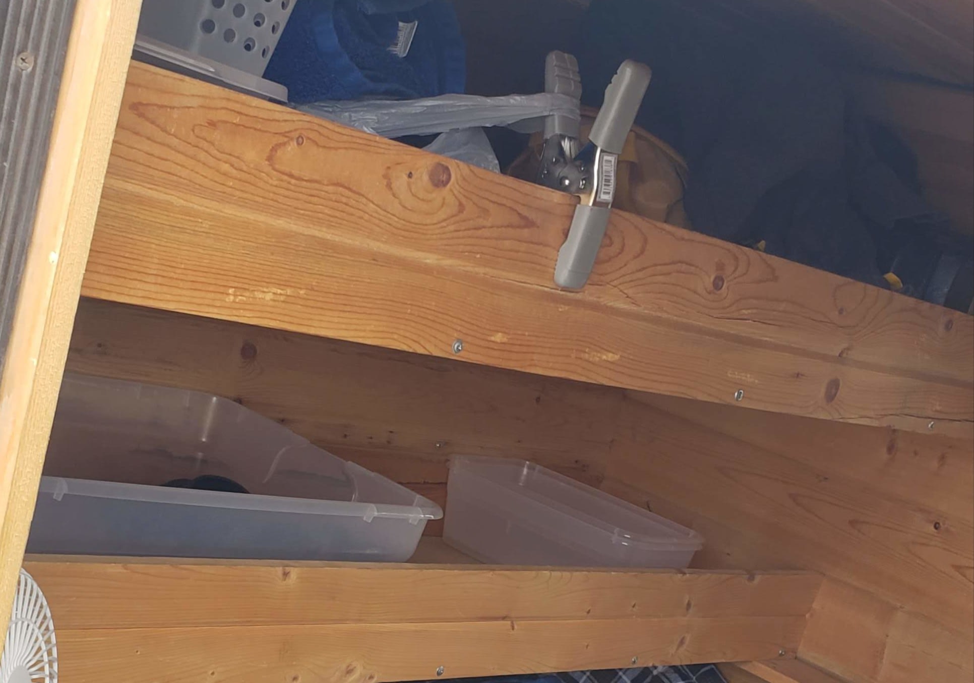 RV rental interior: wooden storage shelves with clear plastic bins, a blue towel, and a gray clamp. Practical organization within tight spaces.. Homemade Teardrop 2020