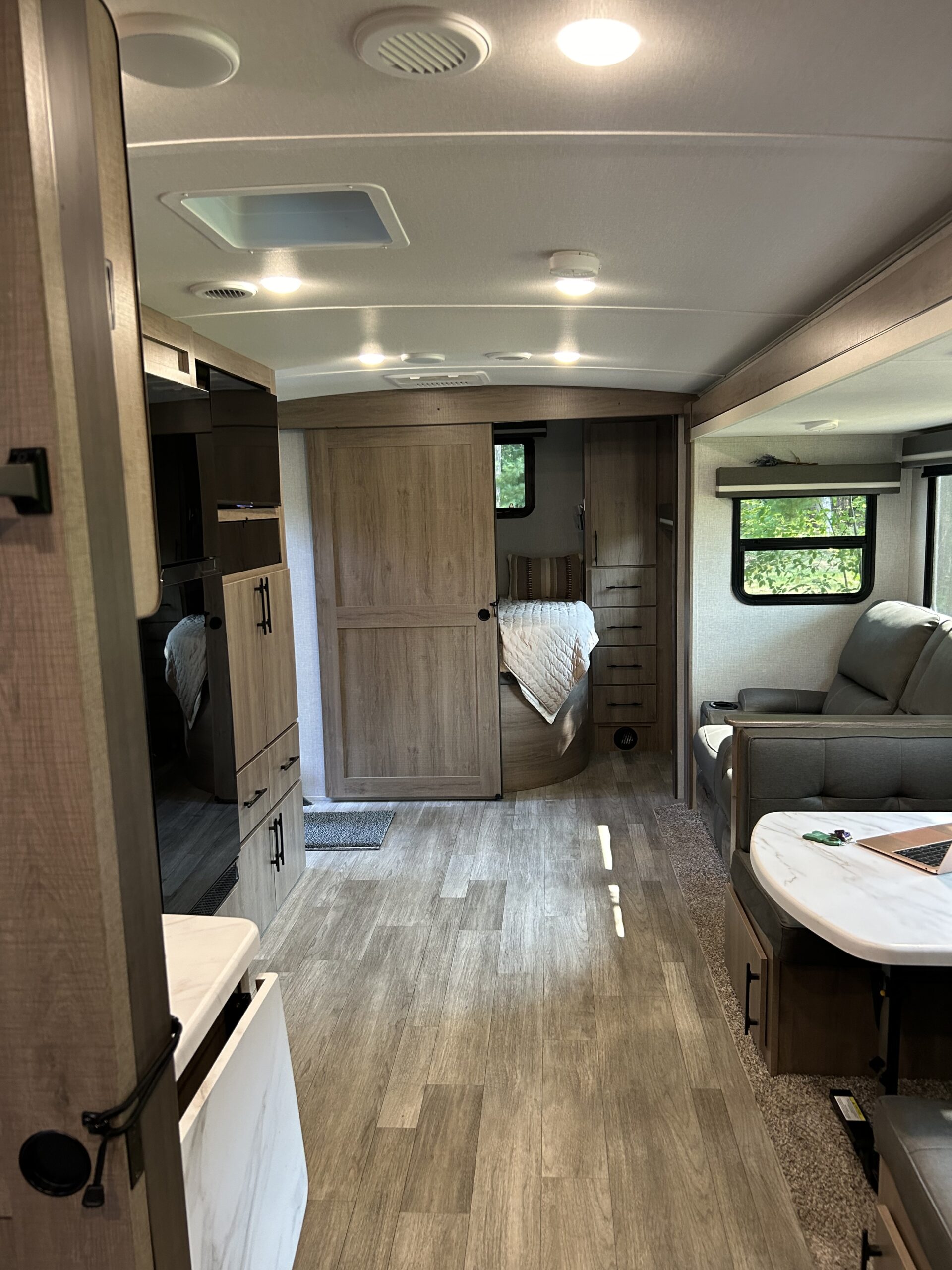 RV rental interior: modern living space with light wood flooring, dining area, and a private master bedroom.. Grand Design Imagine 2024