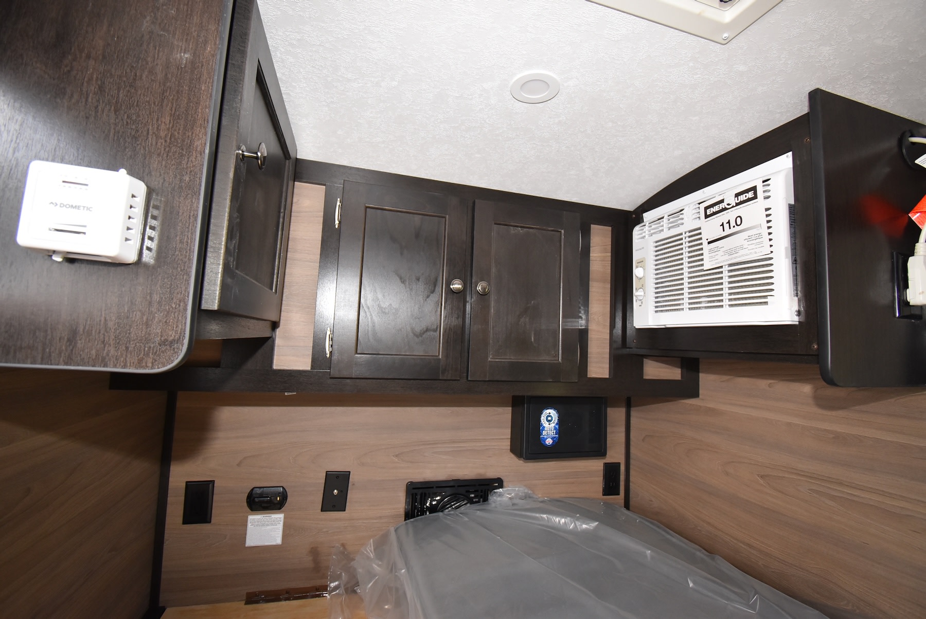 RV rental bedroom with compact overhead storage, Dometic thermostat, window AC unit, and built-in safe for secure travel.. Braxton Creek Bushwhacker 2023