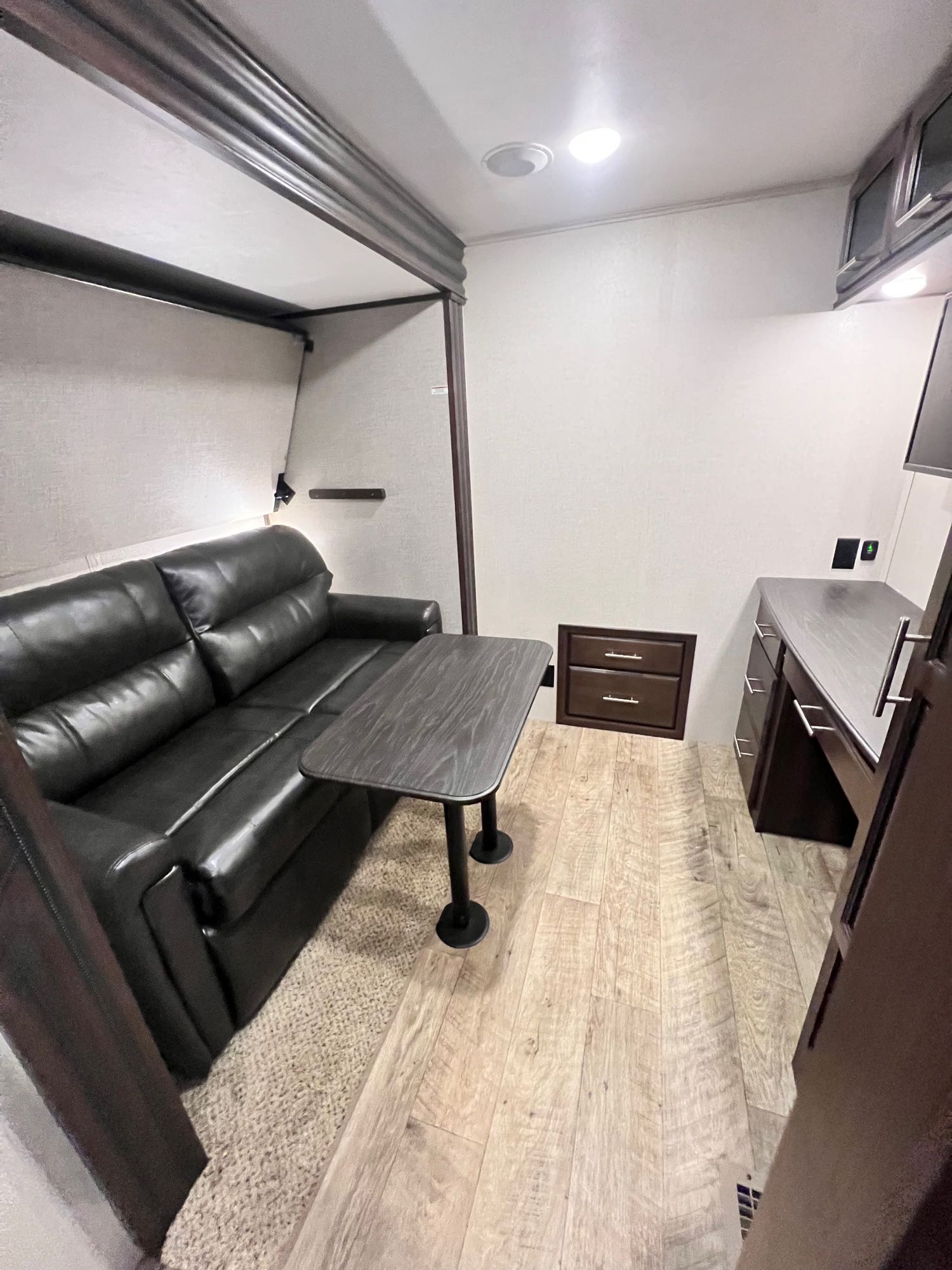 Modern RV rental interior with a dark leather sofa, small table, and desk. Perfect for a cozy road trip adventure.. Jayco North Point 2019