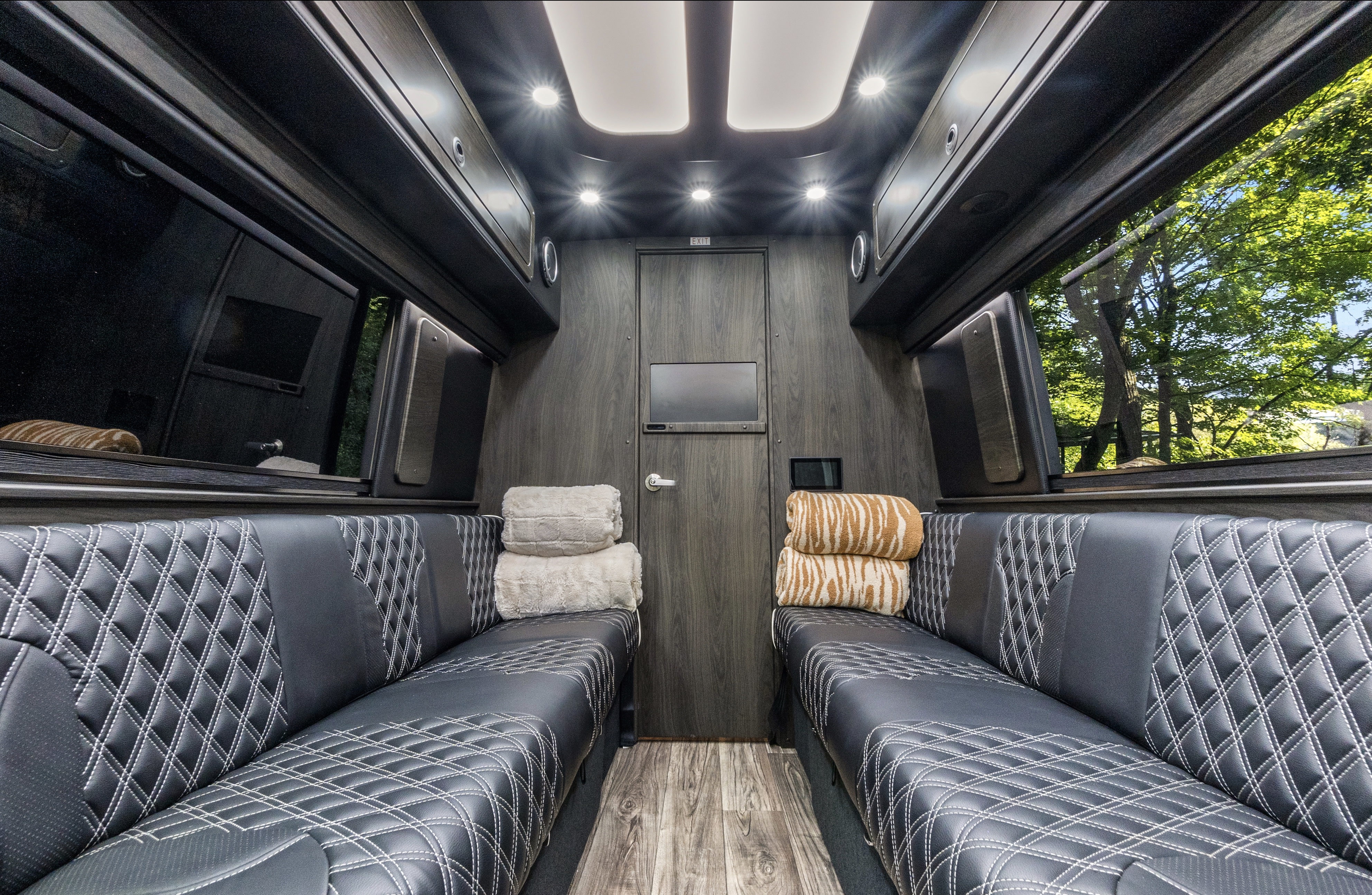 Premium RV rental interior featuring black diamond-stitched seating, wood paneling, and bright cabin lighting.. Mercedes-Benz Sprinter 419 LWB High Roof 2024