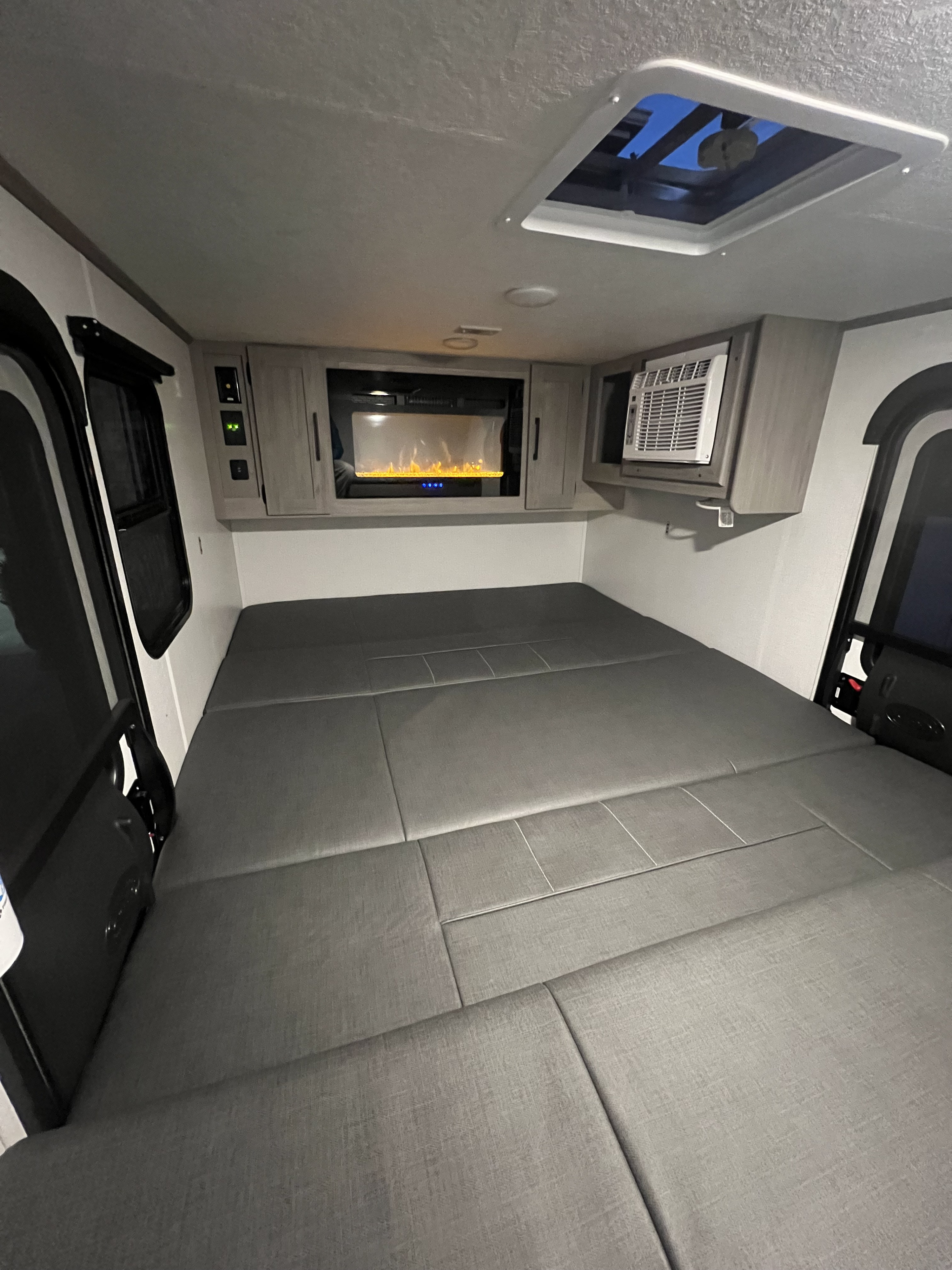 Modern RV rental interior showcasing a large comfortable bed, electric fireplace, and AC unit, ideal for travel adventures.. Dutchmen Rubicon 1400 BH 2024