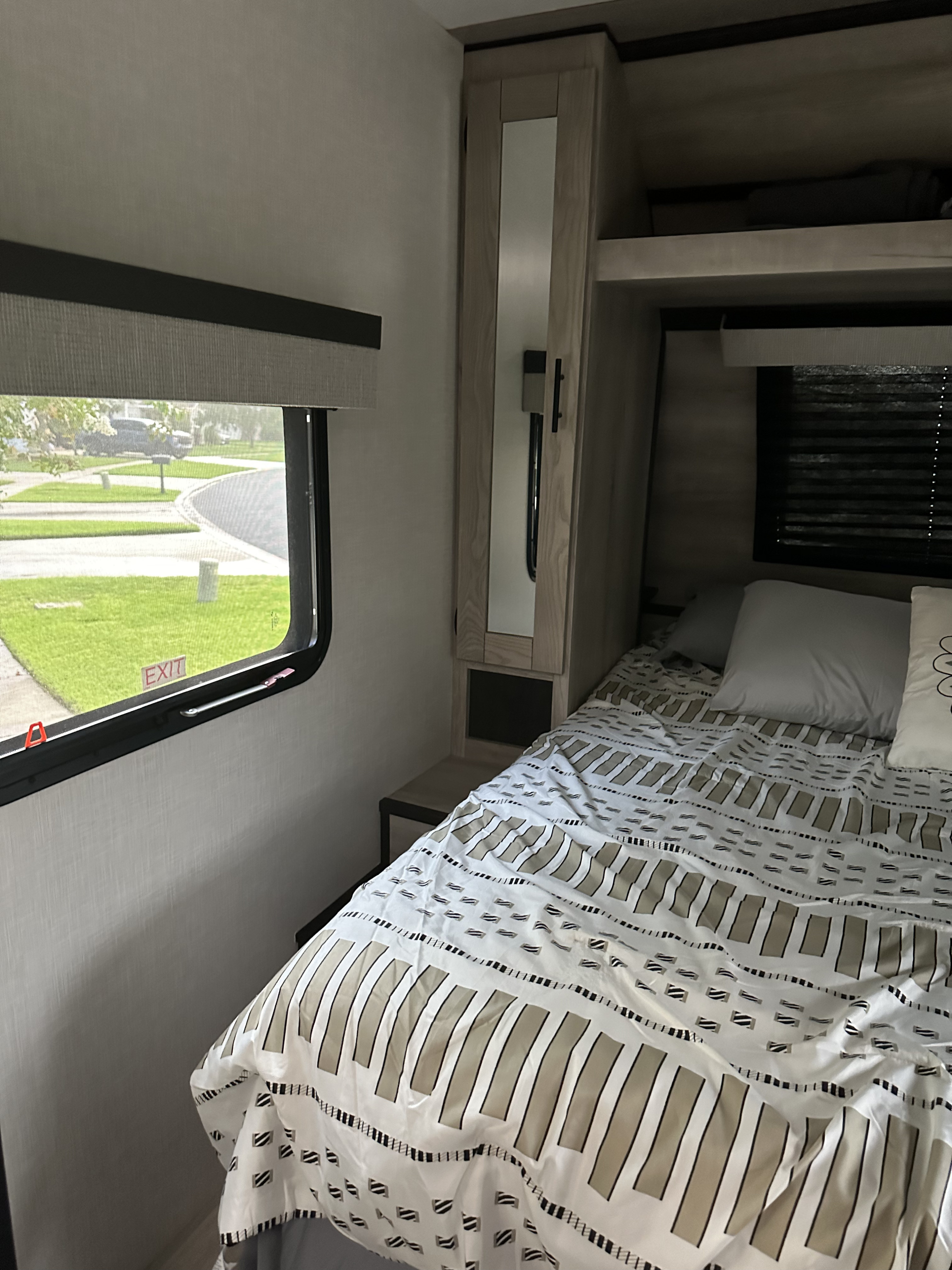 RV rental bedroom interior featuring a patterned bed, window with street view, and built-in storage.. Connect Connect Trailer 2022