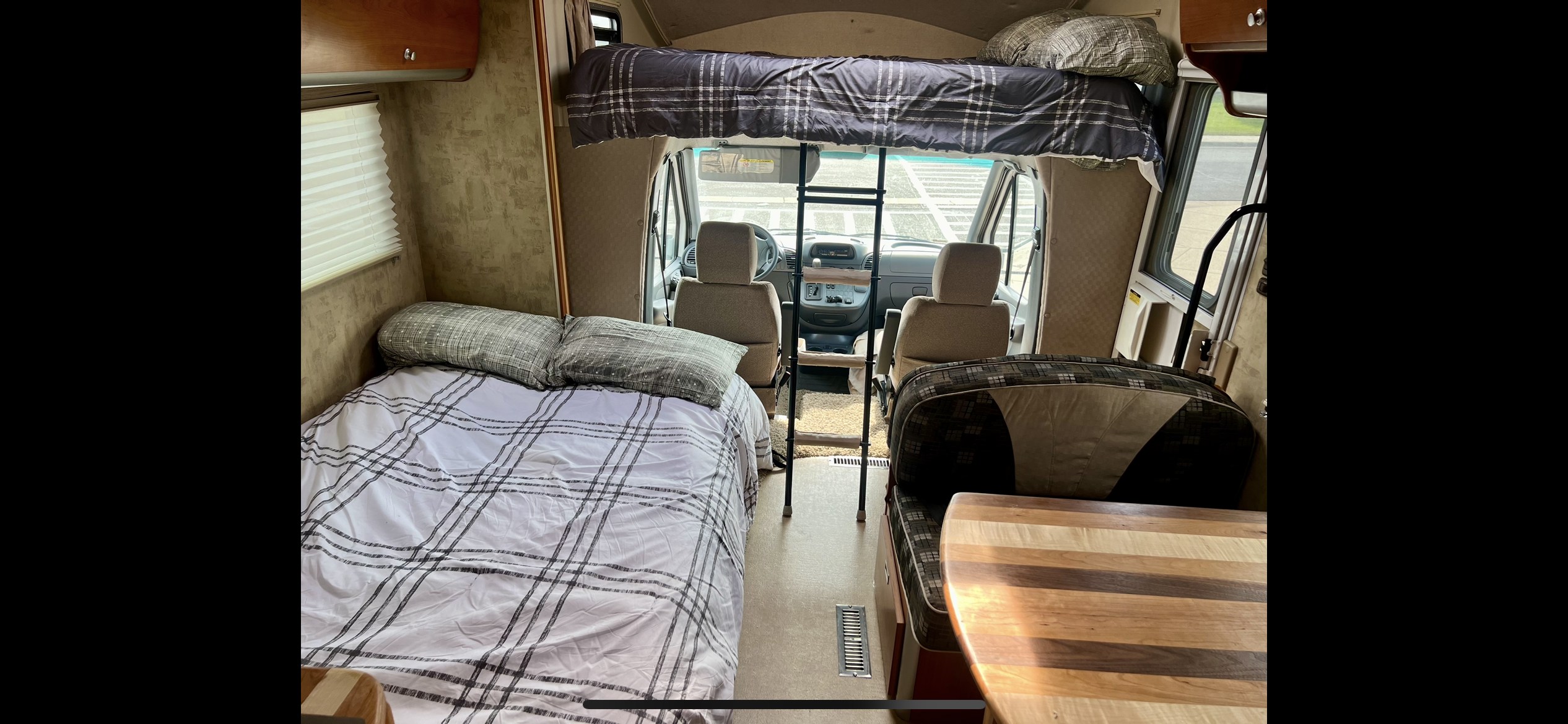 Inside an RV rental: a cozy bed, overhead bunk, and dining area. Perfect compact motorhome interior.. Winnebago View 2007