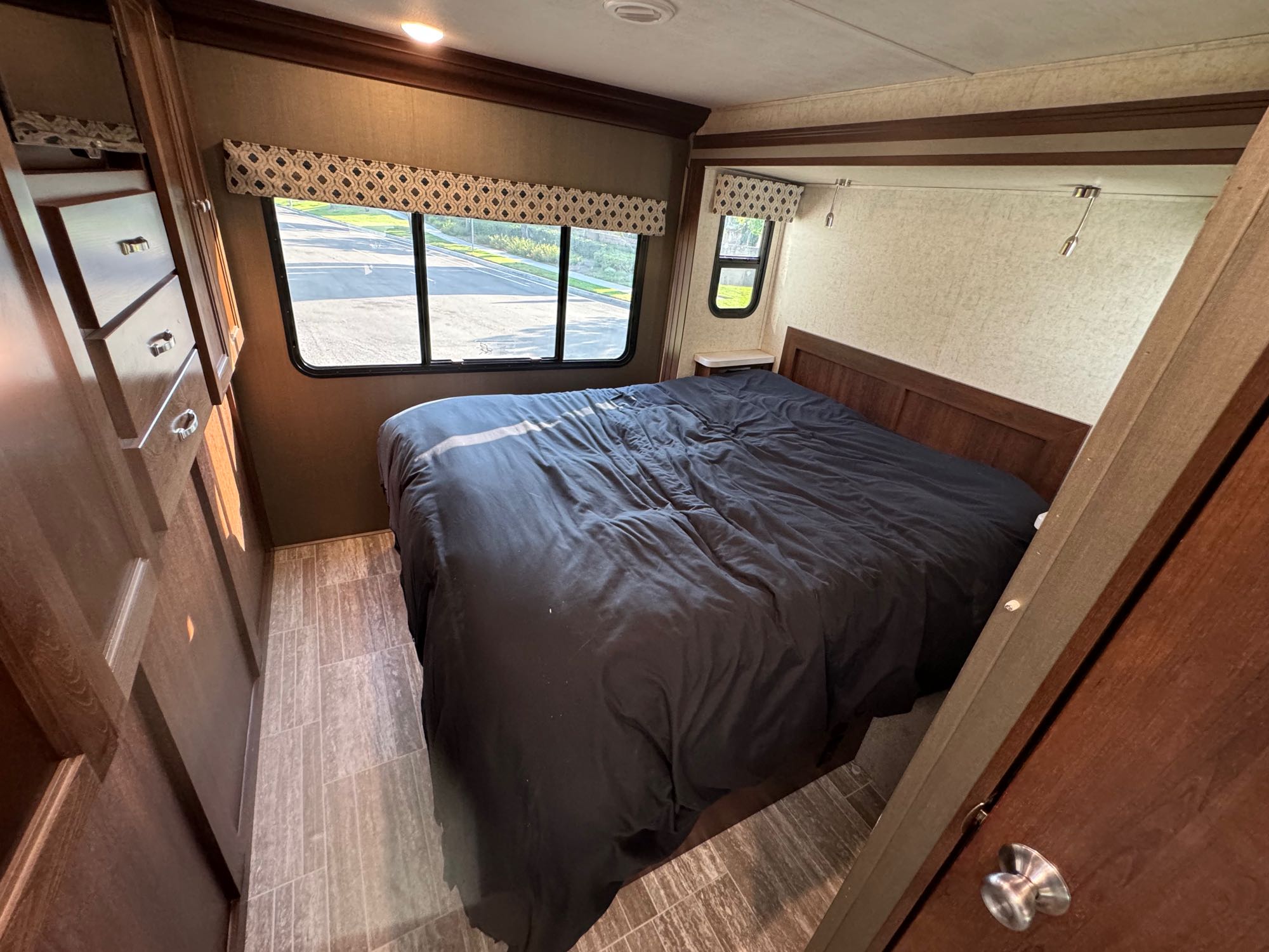 Relaxing RV rental bedroom features a large bed, wooden storage, and windows overlooking the view outside.. Forest River Forester 2019