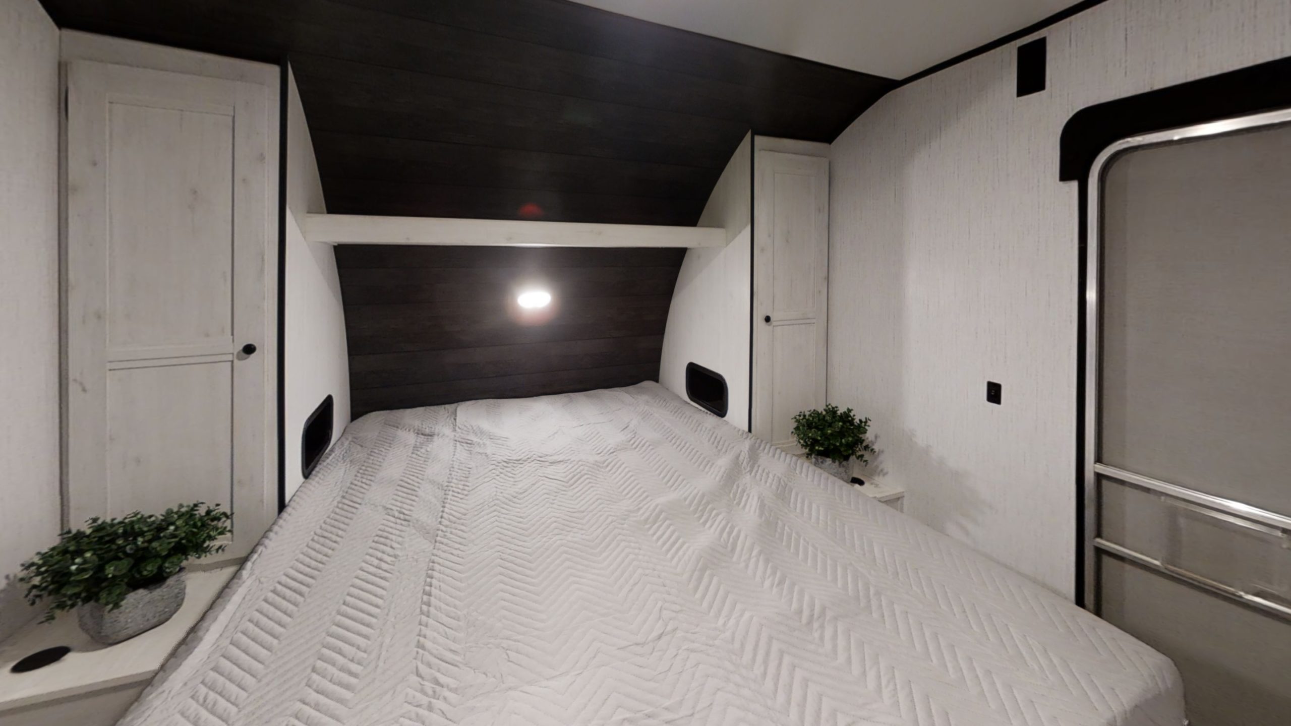 Cozy RV rental bedroom features a queen bed with light gray quilt, light wood cabinets, and dark wood accents. Spacious interior.. Heartland RVs Trail Runner 2022