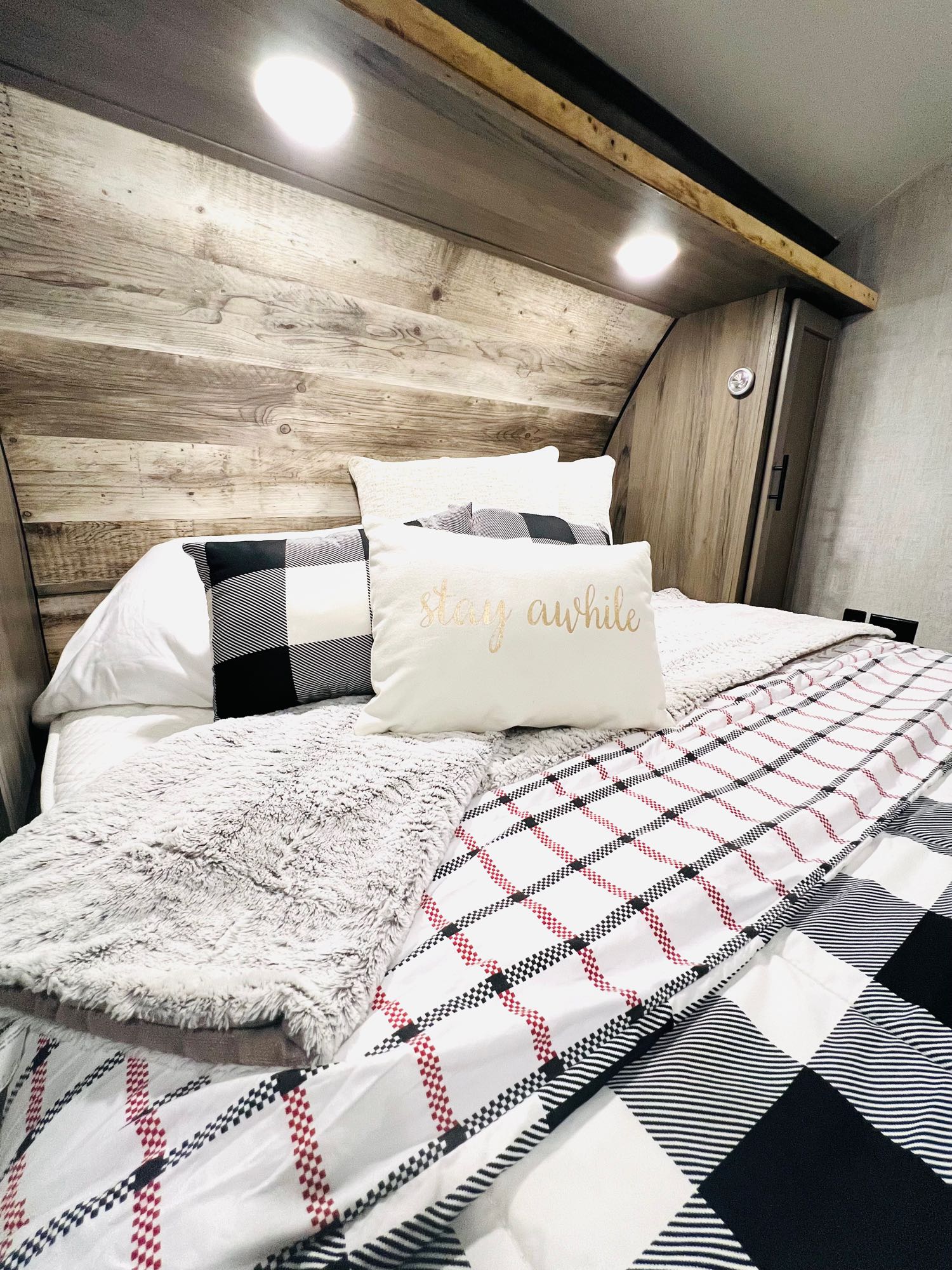 A stylish RV rental bedroom with cozy plaid bedding, a wood headboard, and a fluffy grey blanket creates a welcoming space.. Gulf Stream Gulf Stream 2021