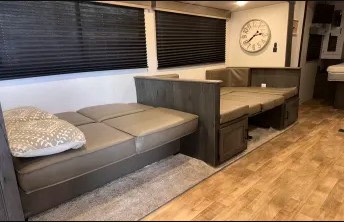 RV rental living space featuring two versatile sofa beds, light wood floor, and window blinds. Perfect for comfy travel.. Keystone RV Hideout 2023