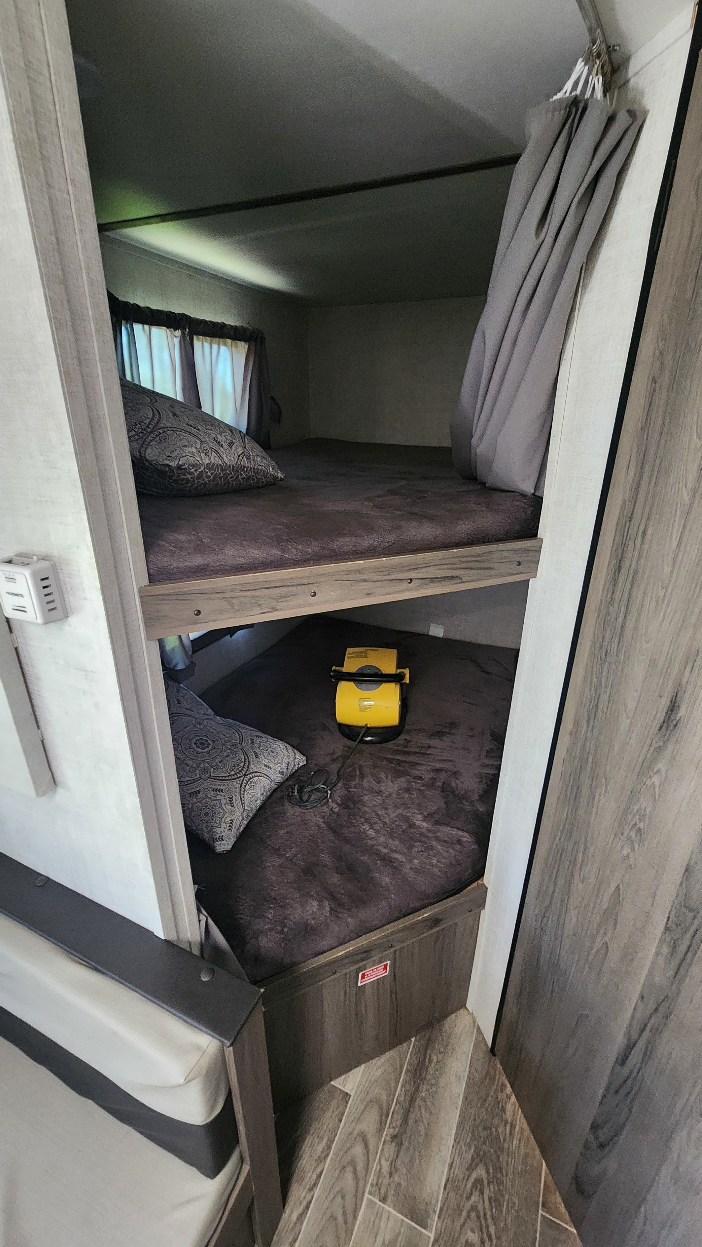 Inside an RV rental, showing a cozy sleeping area with two bunk beds. Features include pillows, a window, and a charger.. Gulf Stream Ameri-Lite Super Lite 2022