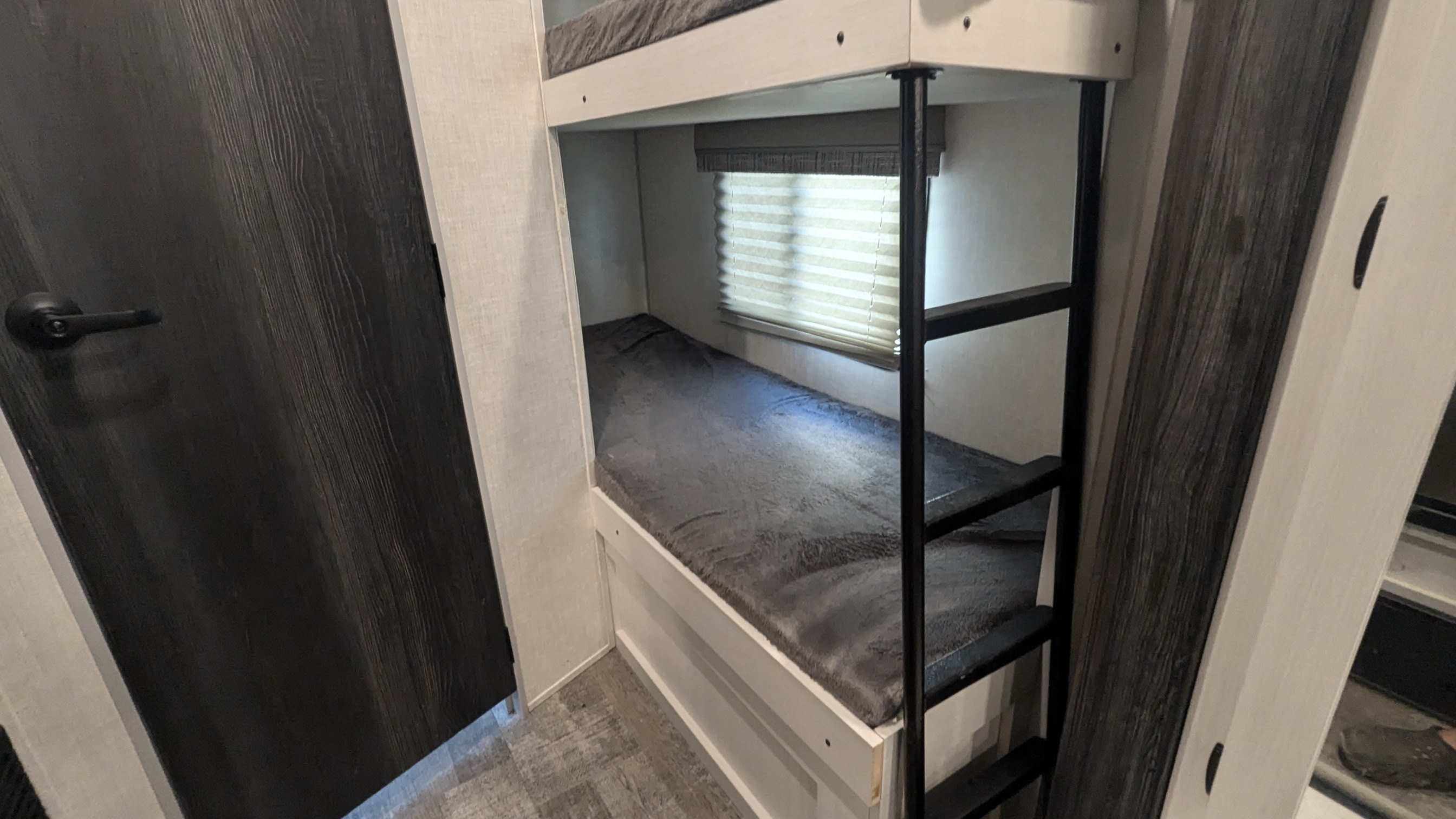 Cozy RV rental bunk beds and a dark wood door, offering a compact sleeping area with a window.. R-Pod R-Pod Trailer 2022