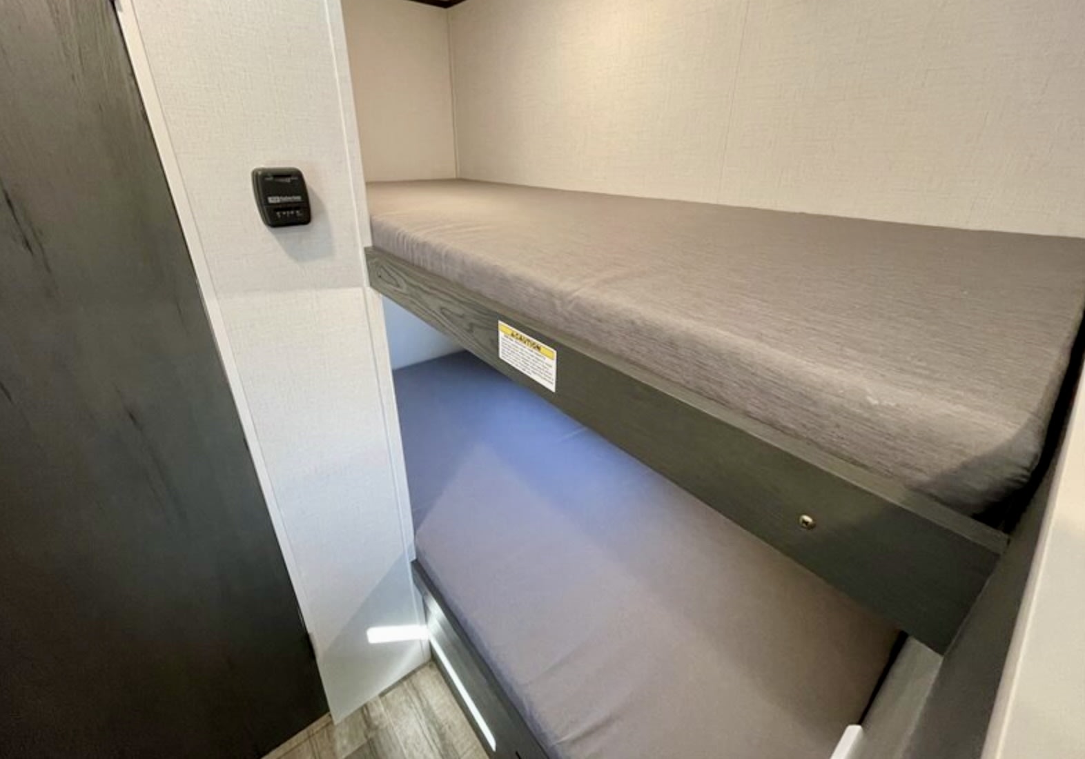 Modern bunk beds in an RV rental, with gray mattresses and practical under-bed lighting, ideal for family travel.. 4YDTATG12S8920000 Dutchmen Aspen Trail 17BH (0000) 2025