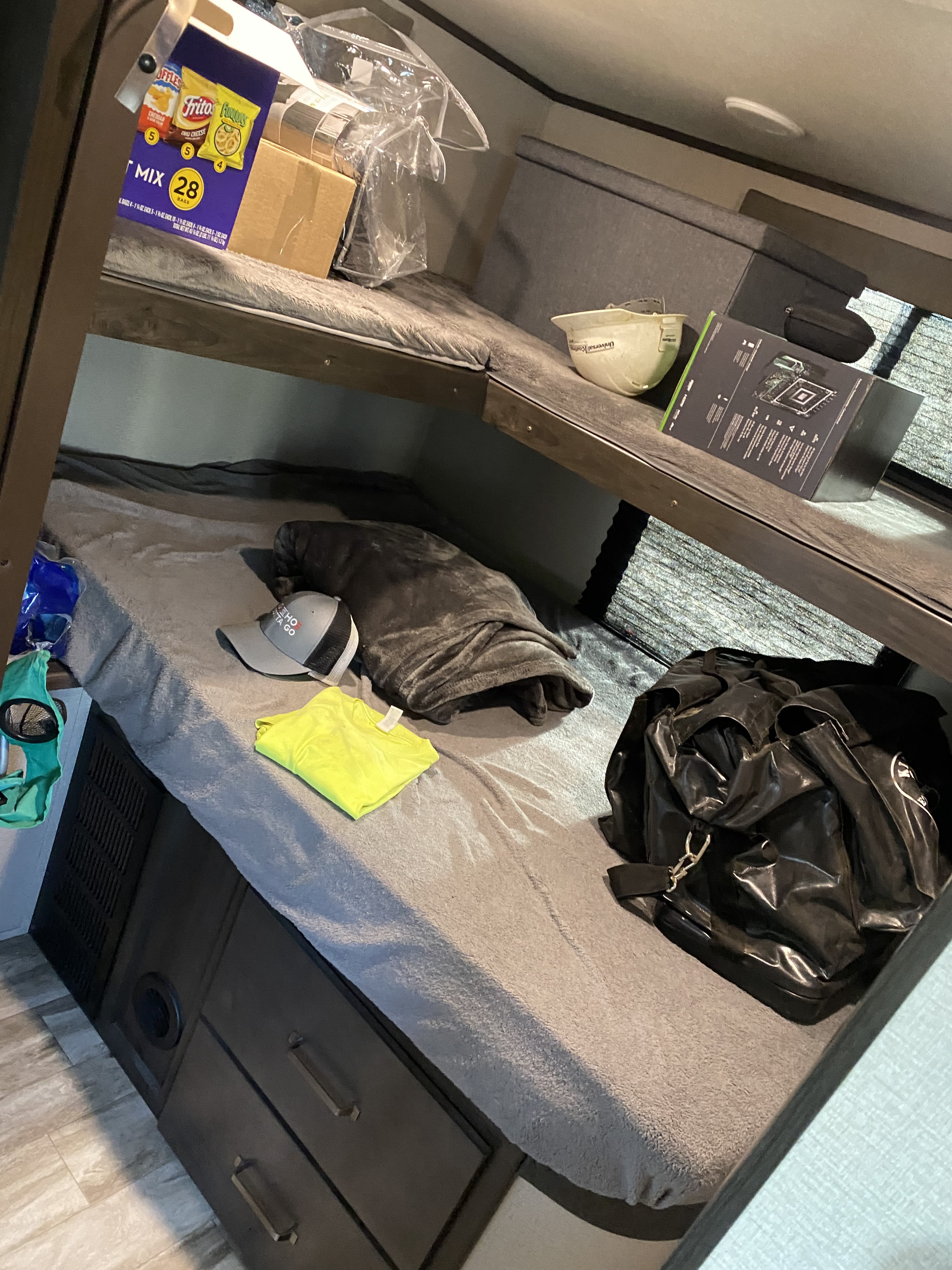 Cozy RV rental bunks with snacks, hard hat, and clothes, showing a comfortable, ready-for-travel interior.. Grand Design Transcend Xplor 2021