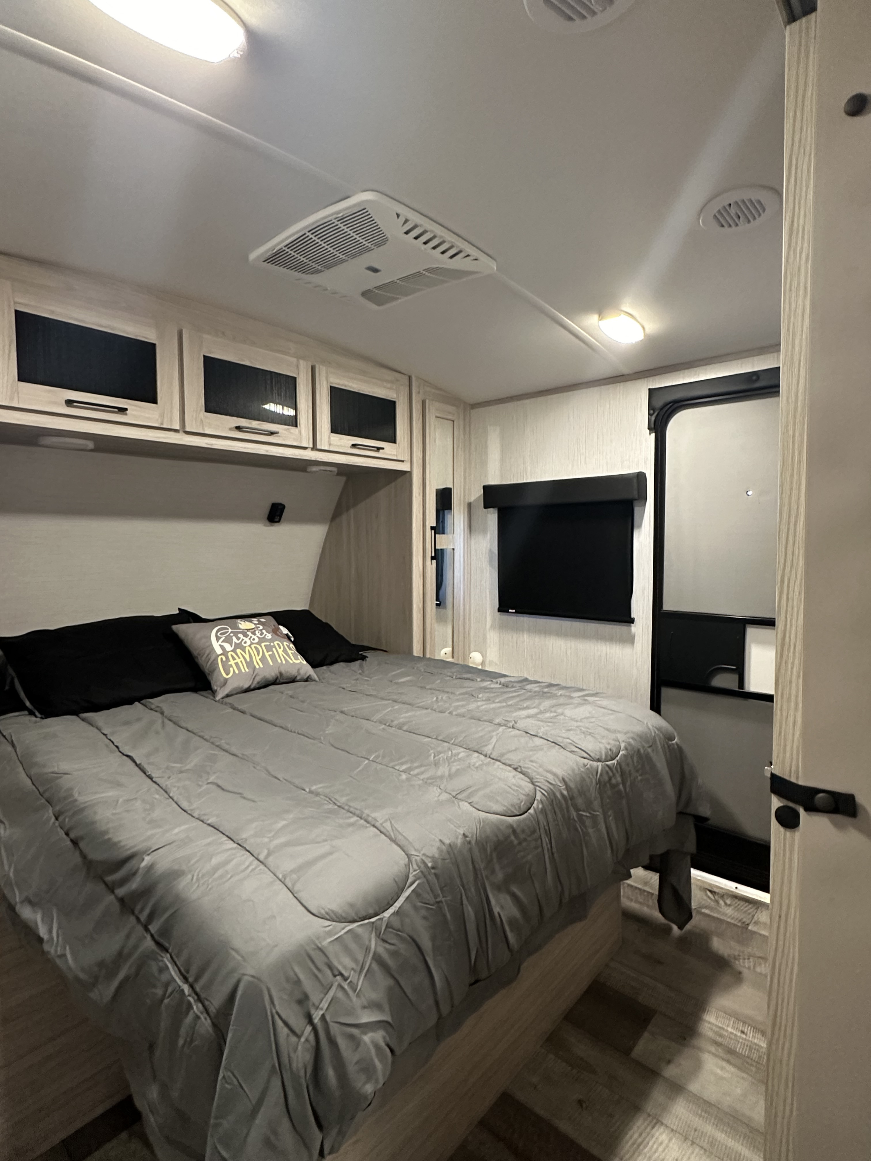Spacious RV rental bedroom with a comfortable bed, sleek cabinets, wall-mounted TV, and ceiling AC unit.. Heartland RVs Sundance Ultra Lite 2022