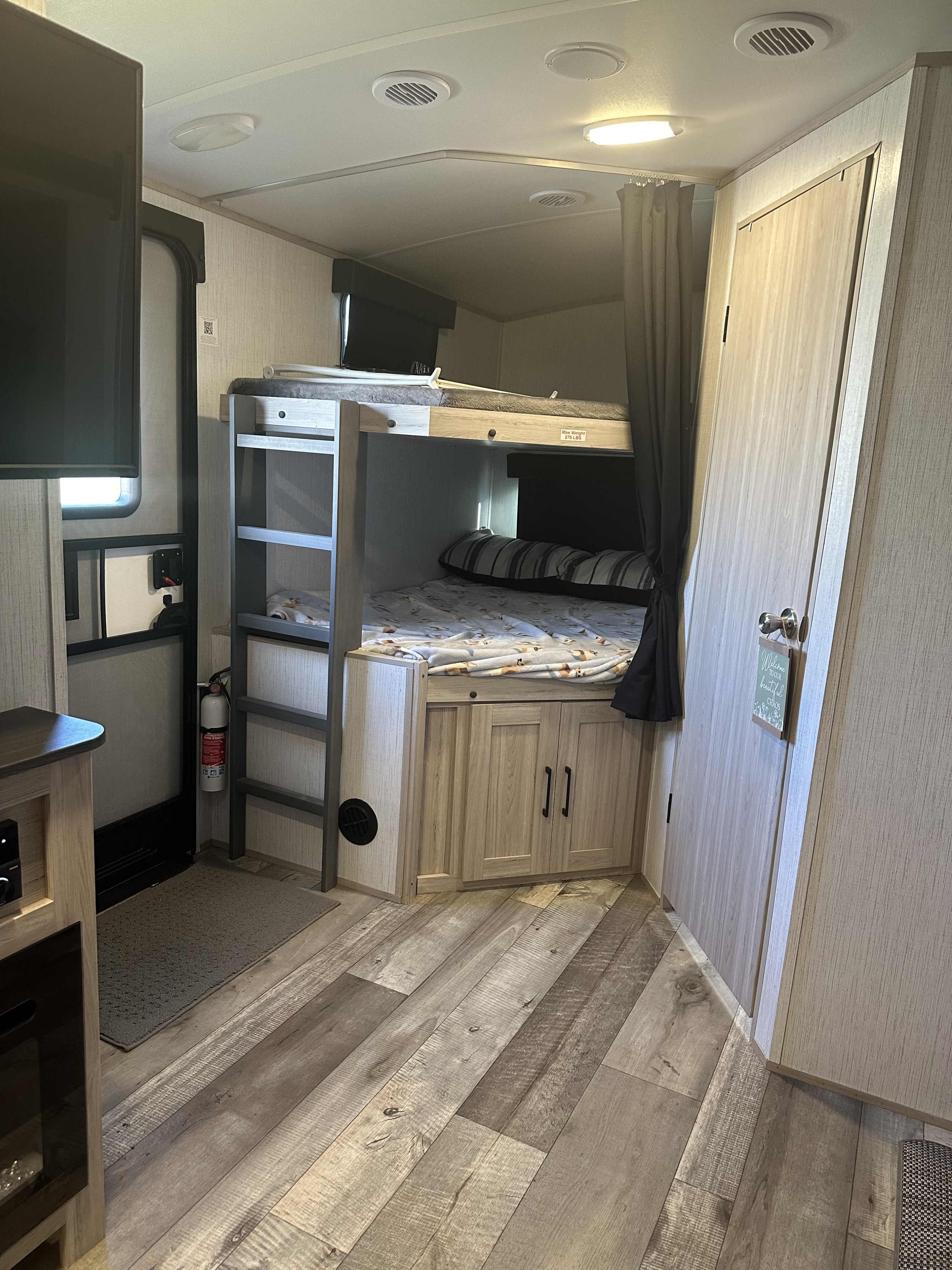 This RV rental interior features modern bunk beds with soft bedding, light wood finishes, and durable flooring.. Heartland RVs Sundance Ultra Lite 2022