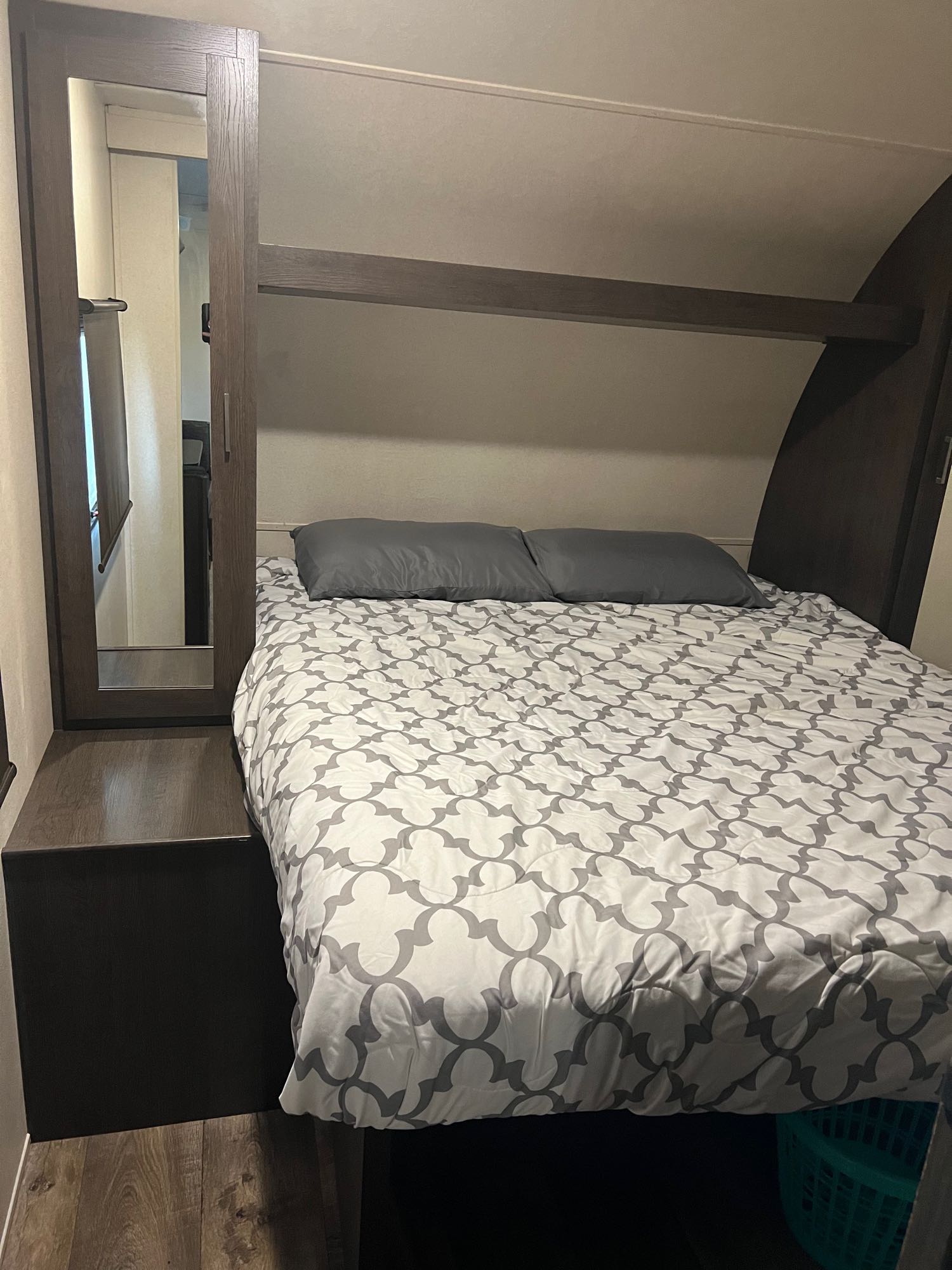 Cozy RV rental bedroom features a bed with a patterned comforter, mirrored wardrobe, and overhead storage.. Forest River Salem 2019