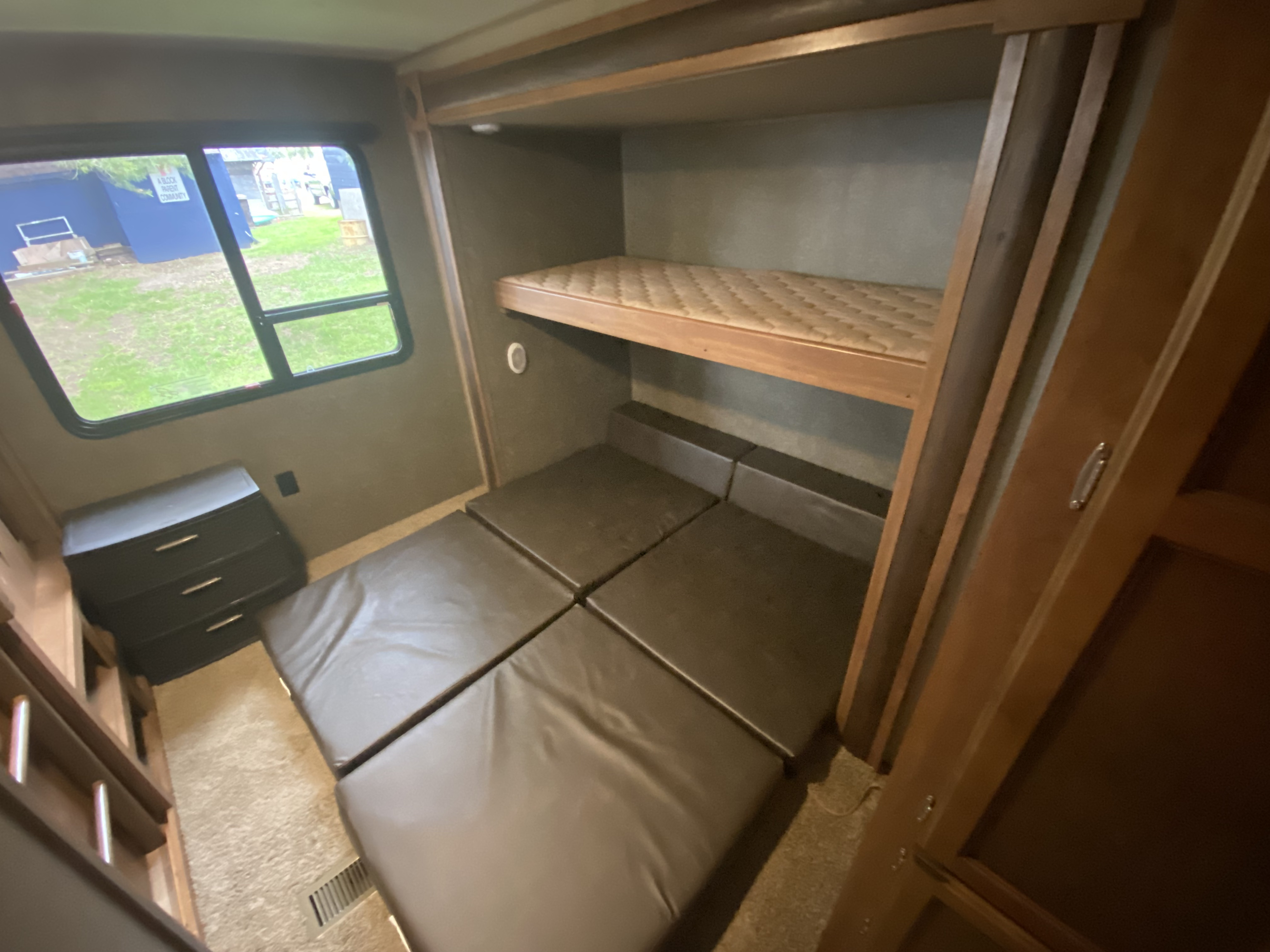 RV rental interior: Bunk beds above, convertible floor cushions below, and a window view of an 'A Block Parent Community'.. Keystone RV Summerland 2018