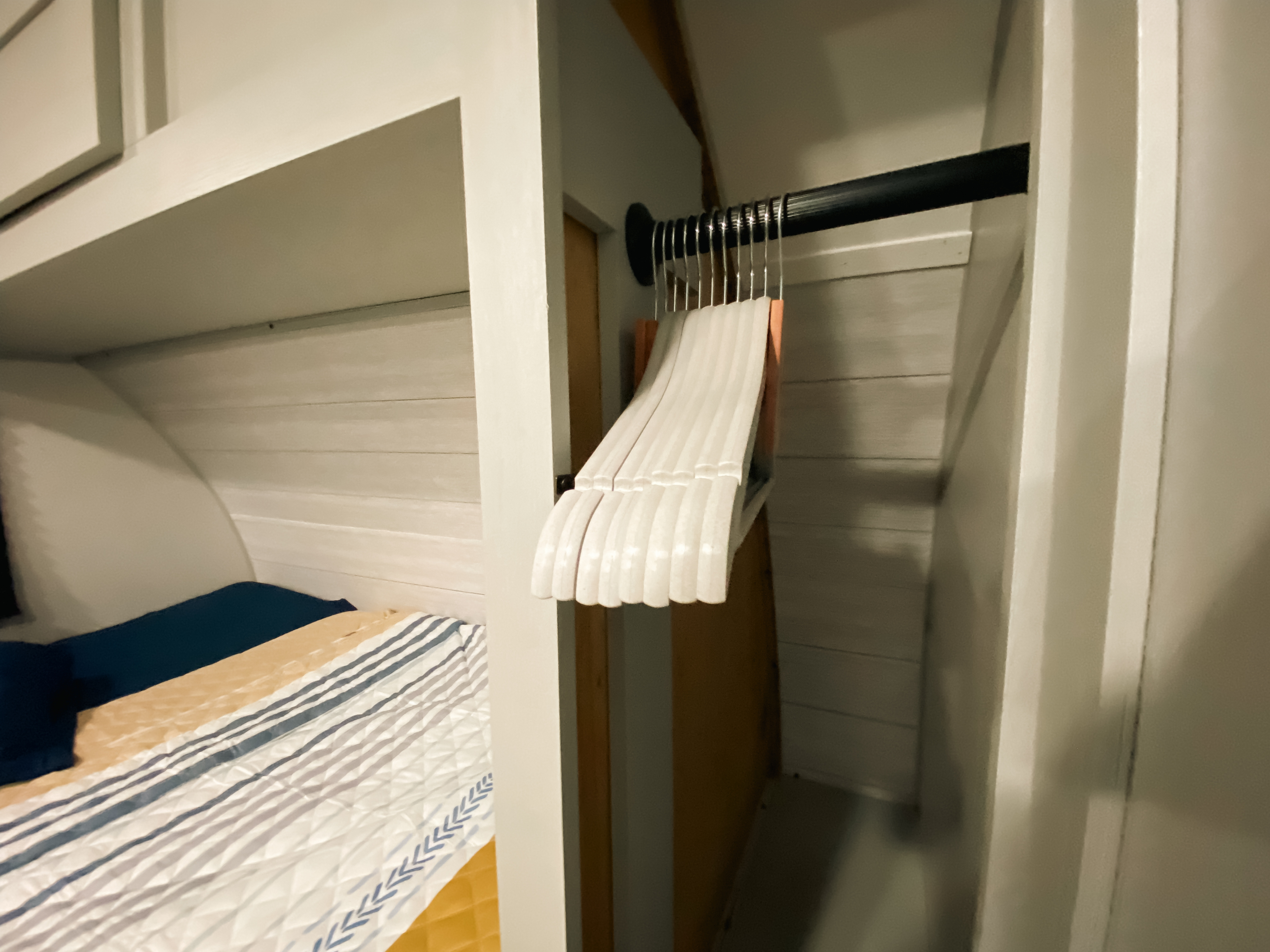 Inside an RV rental, a compact bedroom features a cozy bed with striped bedding & a closet with white hangers.. Forest River Salem FSX PLATINUM 2021