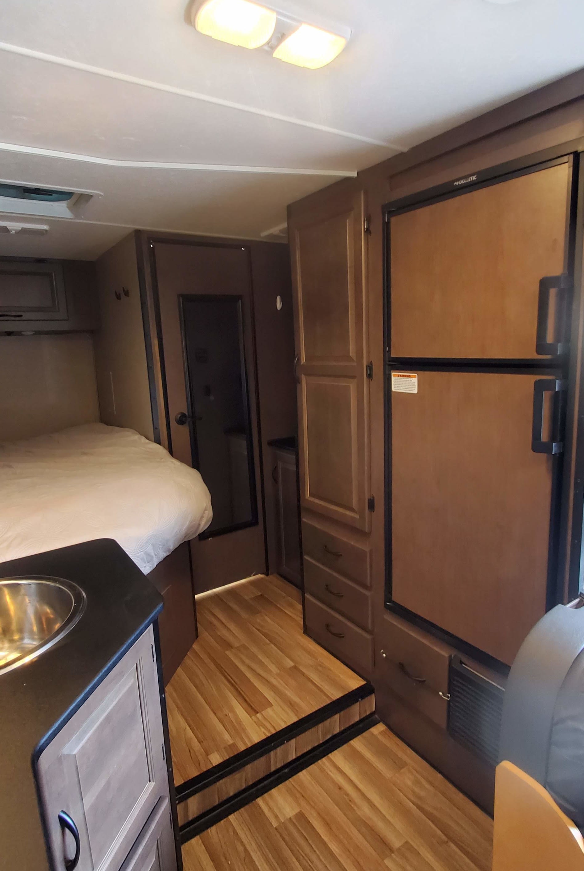 Spacious RV rental interior with a comfortable bed, functional kitchenette, and large refrigerator.. Wayfarer T23 2020