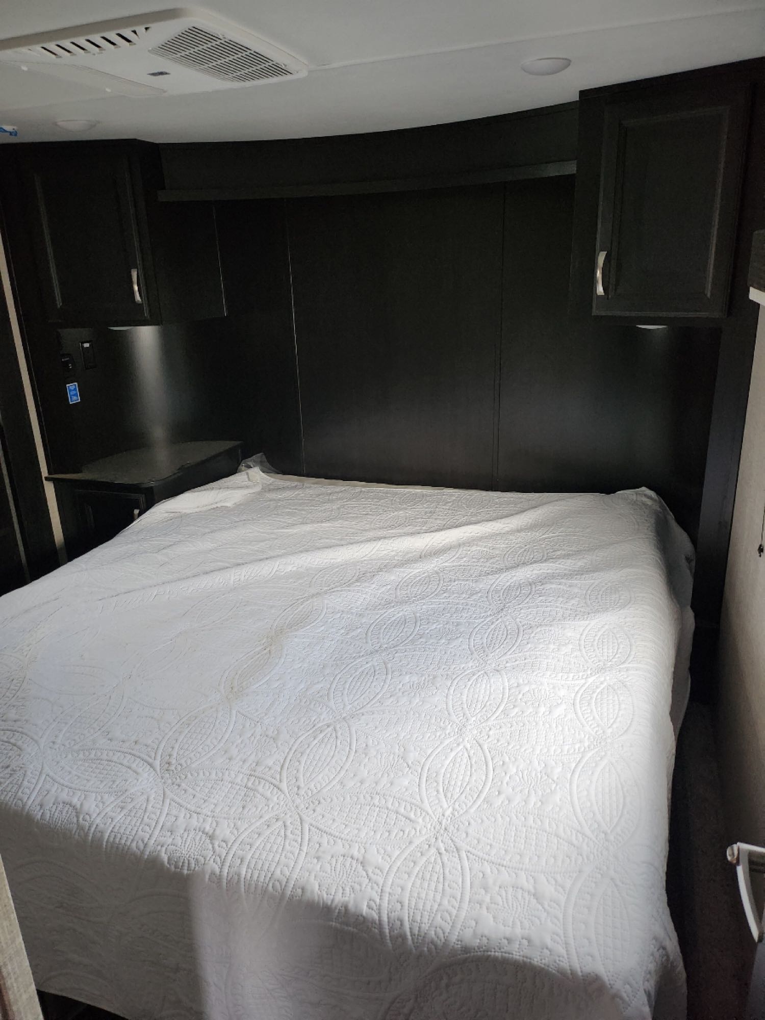 Cozy RV rental bedroom with white quilted bed, dark cabinets, and AC. Ready for your travels!. Jayco Seismic 2023