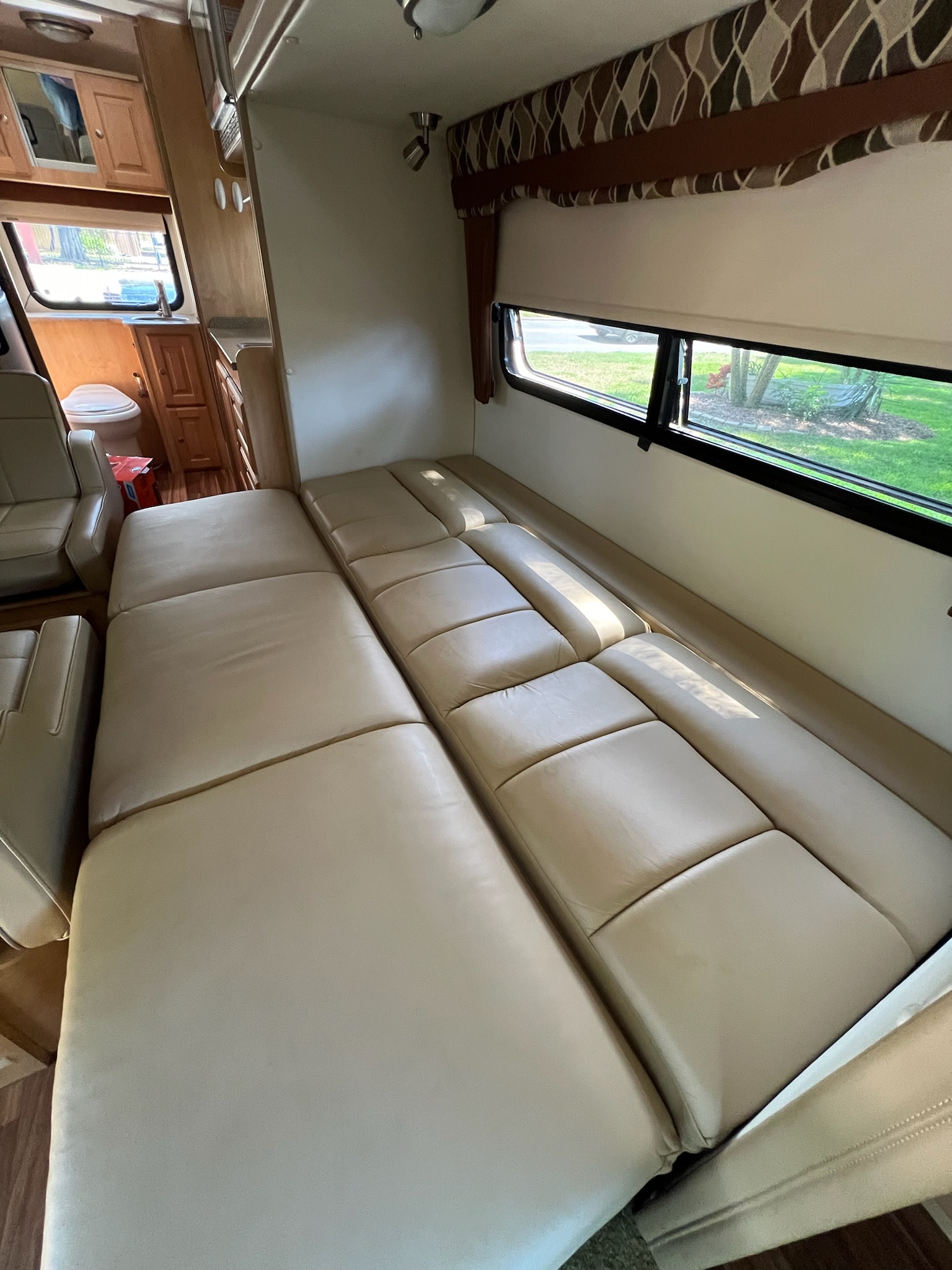 Spacious RV rental interior featuring a convertible sofa bed, captain's chairs, and a compact bathroom.. Coach House Platinum II 2015