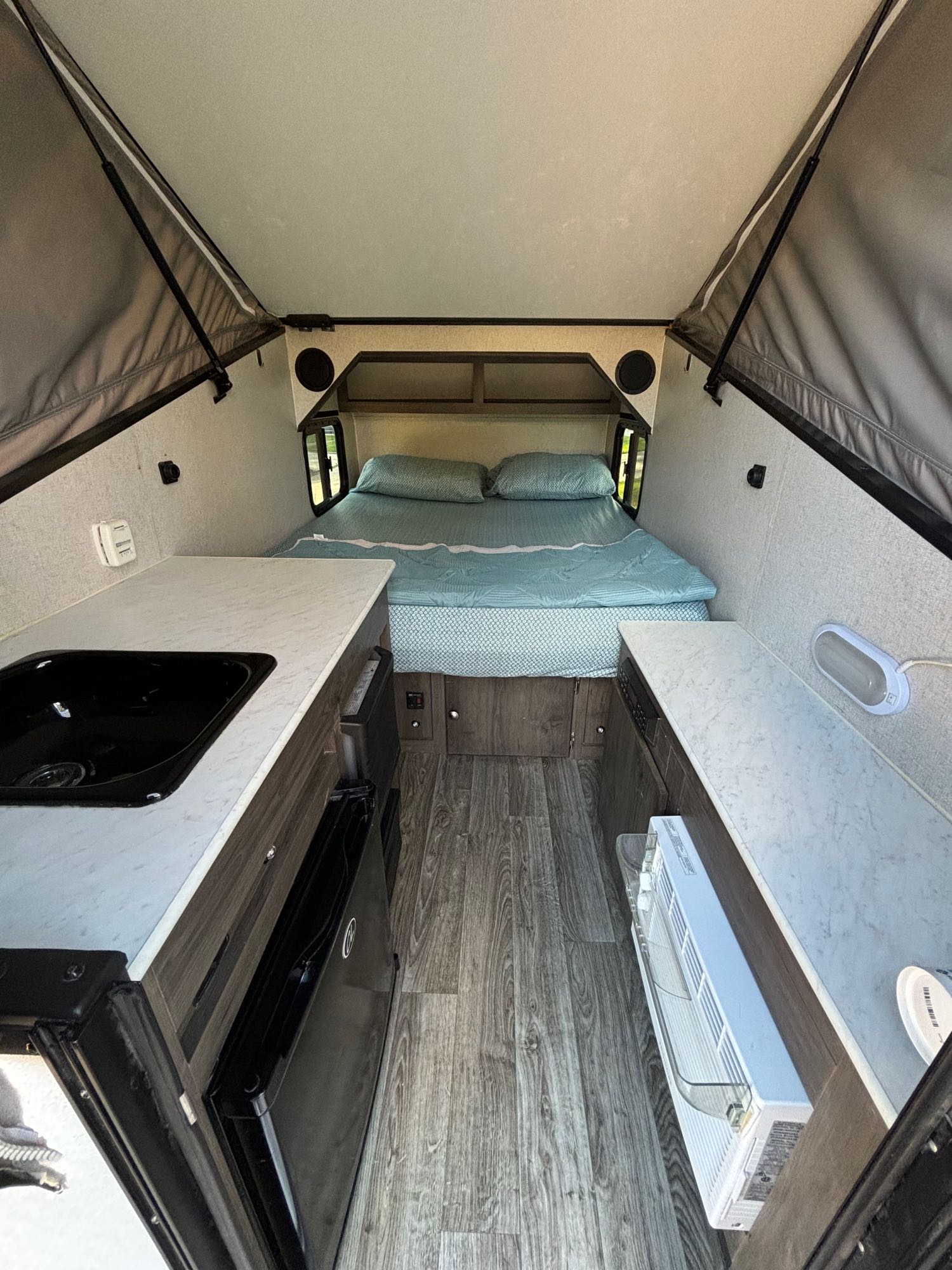 Inside an RV rental, featuring a comfortable bed, kitchenette with sink, fridge, and AC unit for your adventure.. Forest River Viking 2020