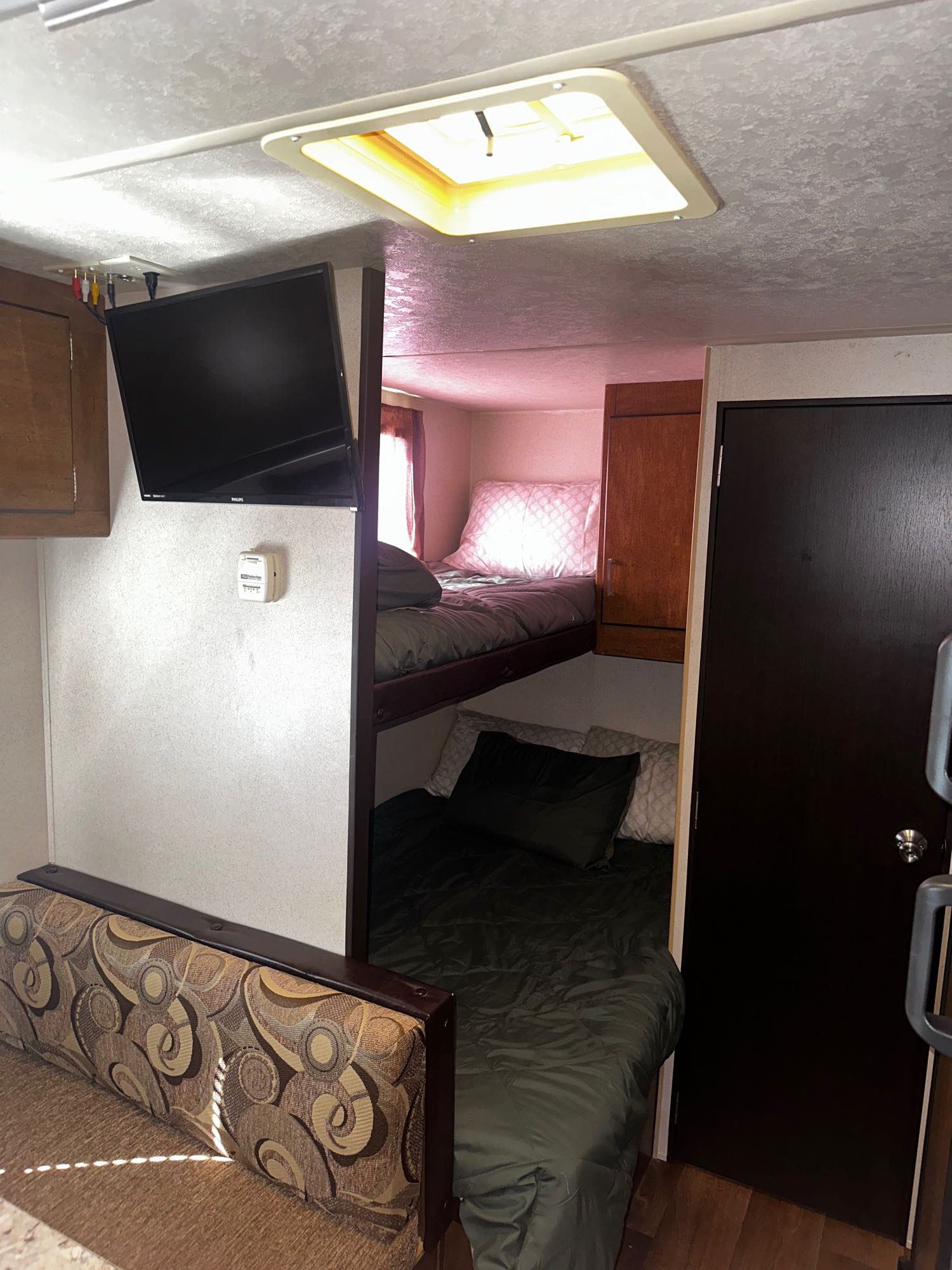 Inside this RV rental: compact living area with bunk beds, a sofa, wall-mounted TV, and a thermostat.. Forest River Salem Cruise Lite 2018