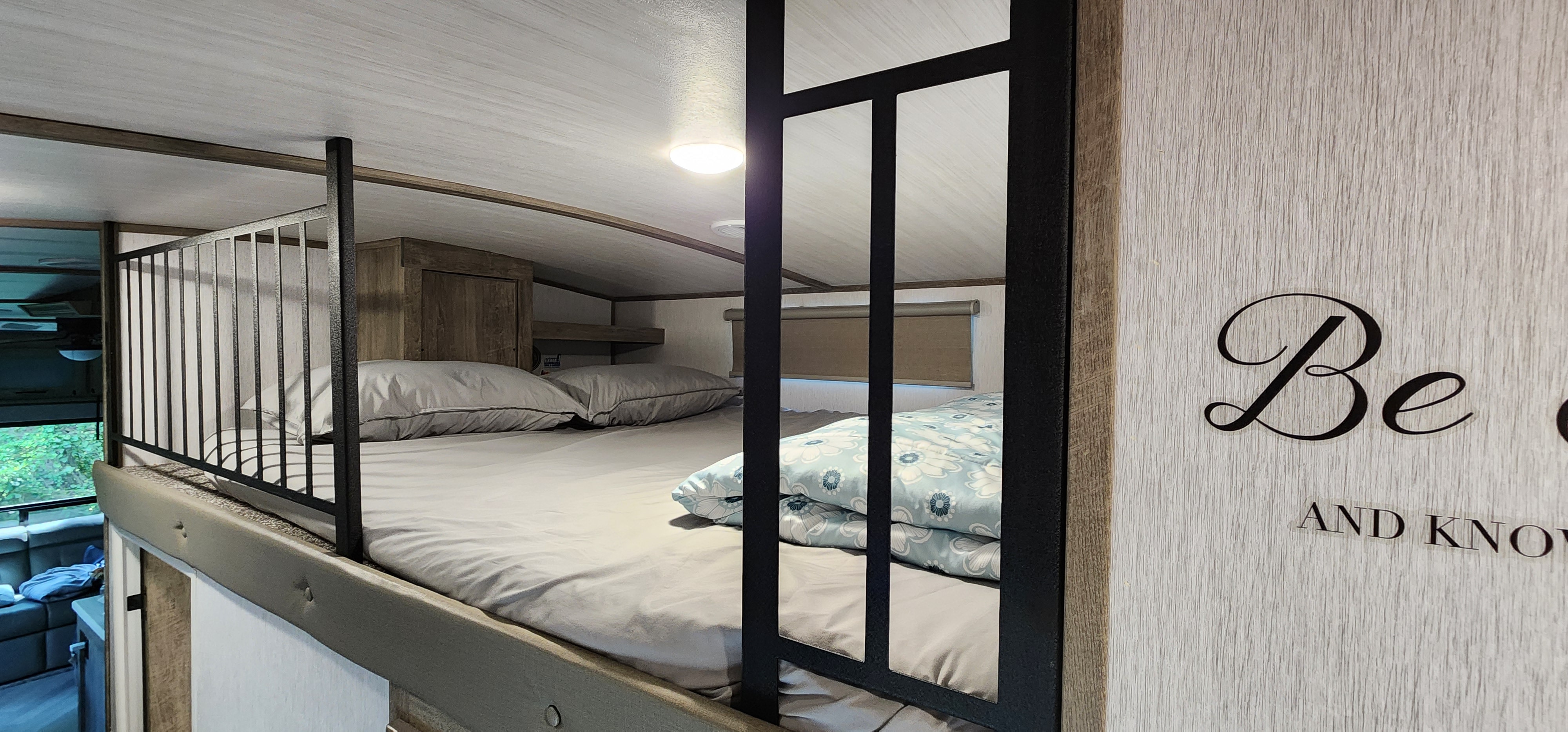 Cozy RV rental loft featuring bunk beds with bedding, a decorative rail, and a light fixture for comfortable stays.. Forest River Hemisphere 2022